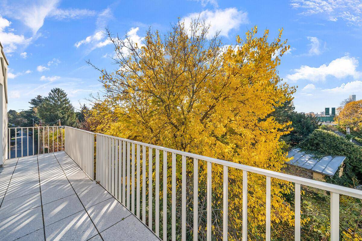 Großer Balkon mit Blick auf herbstliche Bäume und die grüne Umgebung.