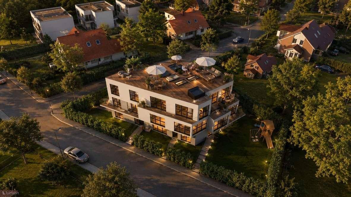 Luftaufnahme der modernen Wohnanlage bei Sonnenuntergang mit beleuchteter Dachterrasse und Garten.