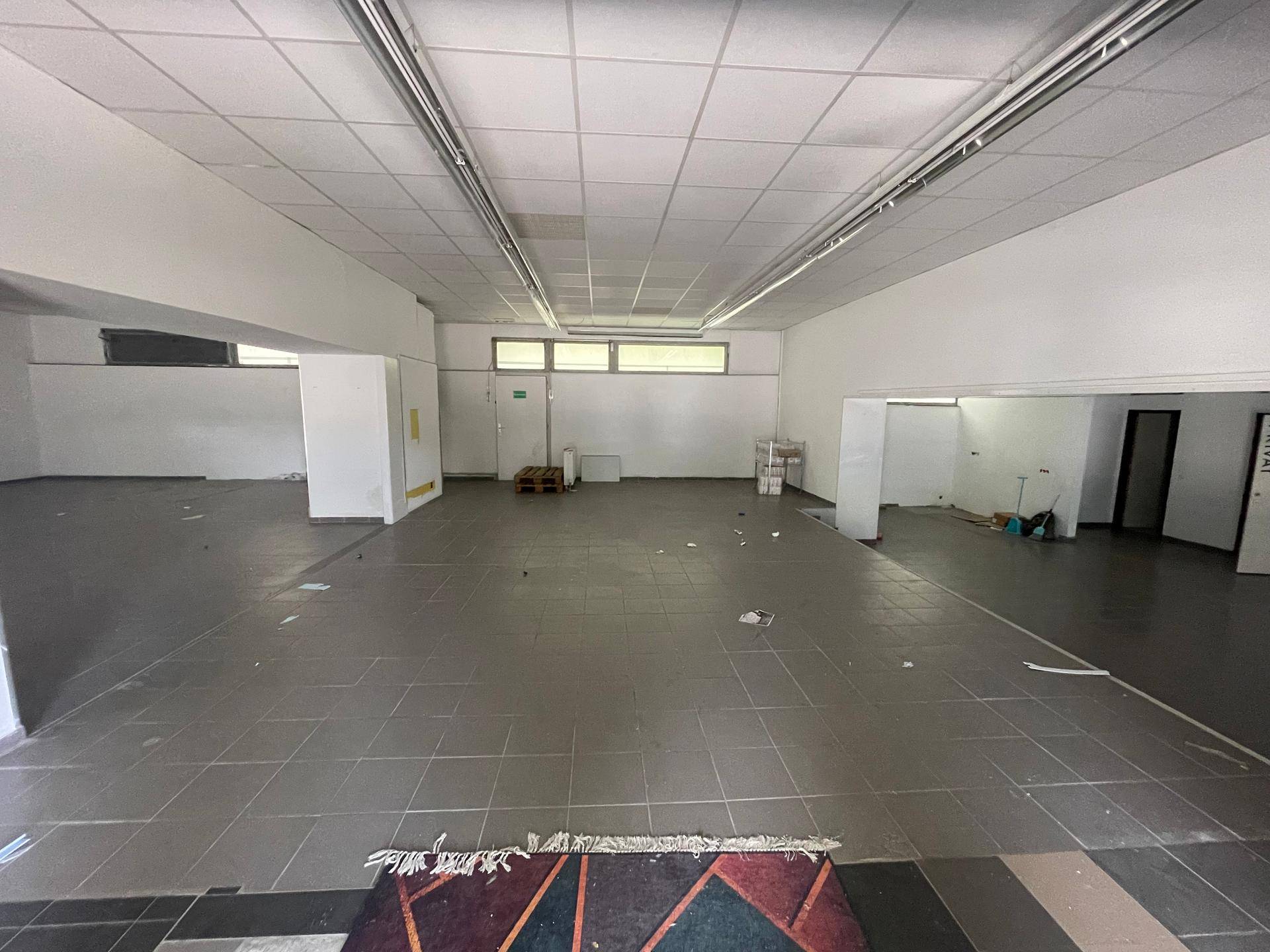 Heller und geräumiger Gewerberaum mit Fliesenboden und einer abgehängten Decke.