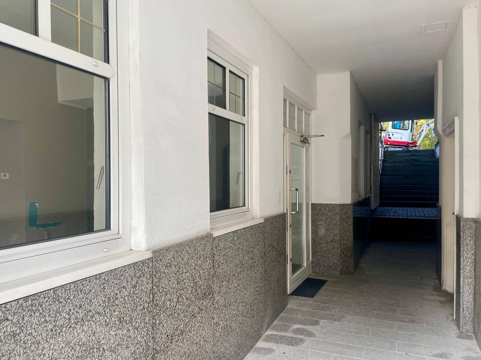 Heller Durchgang mit Granitsockel und Blick auf eine Treppe im Hintergrund, die nach oben führt.