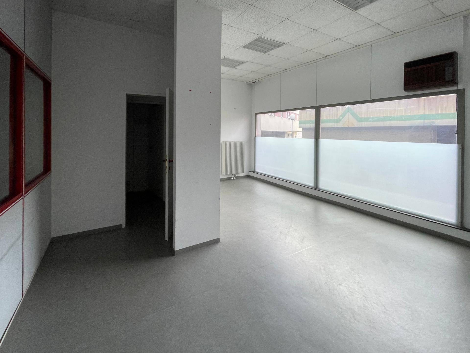 Großer, heller Gewerberaum mit breiten Fenstern und einem Heizkörper an der Wand.