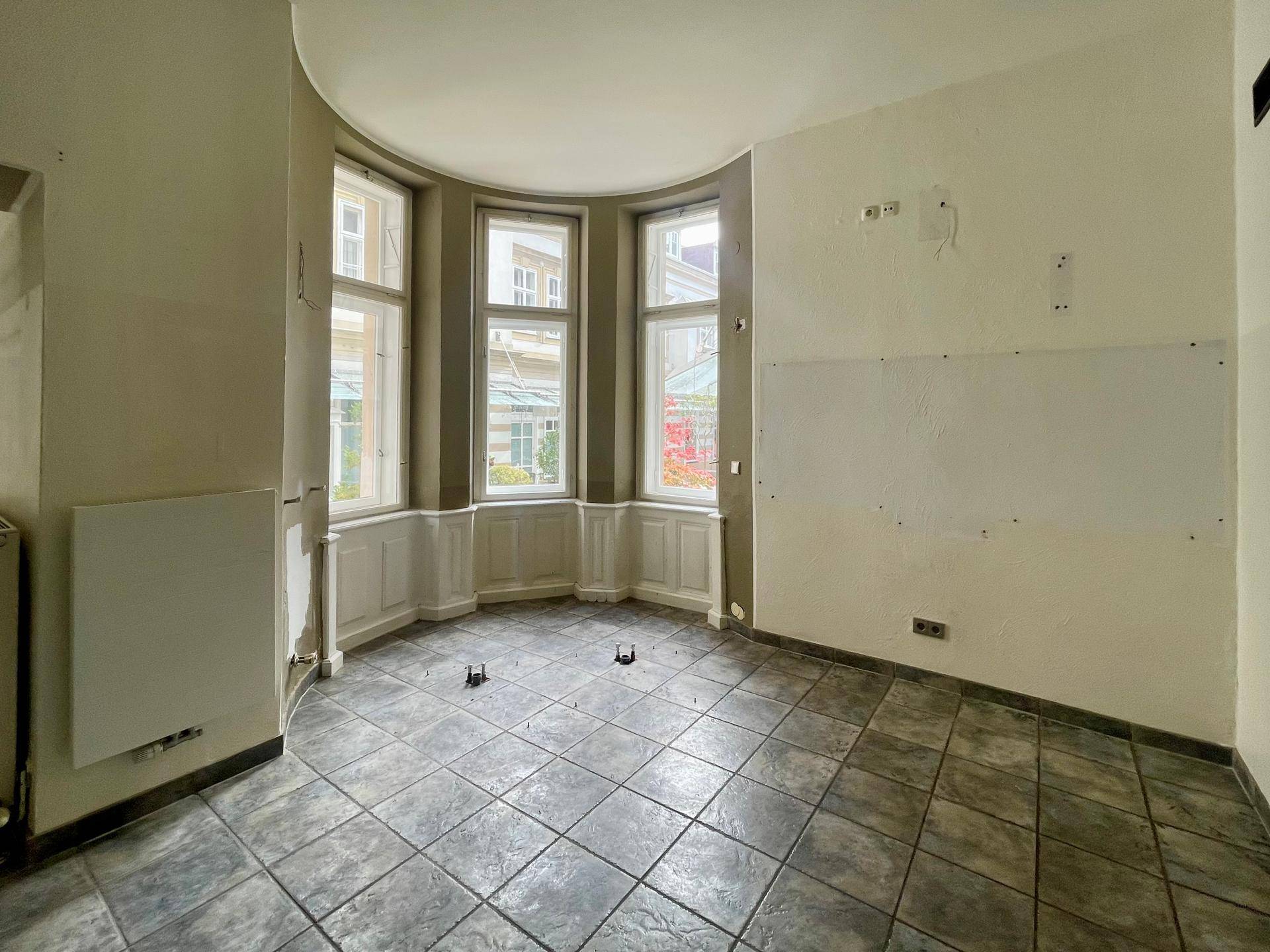 Gewerberaum mit charakteristischem Erkerfenster, Fliesenboden und viel natürlichem Lichteinfall.