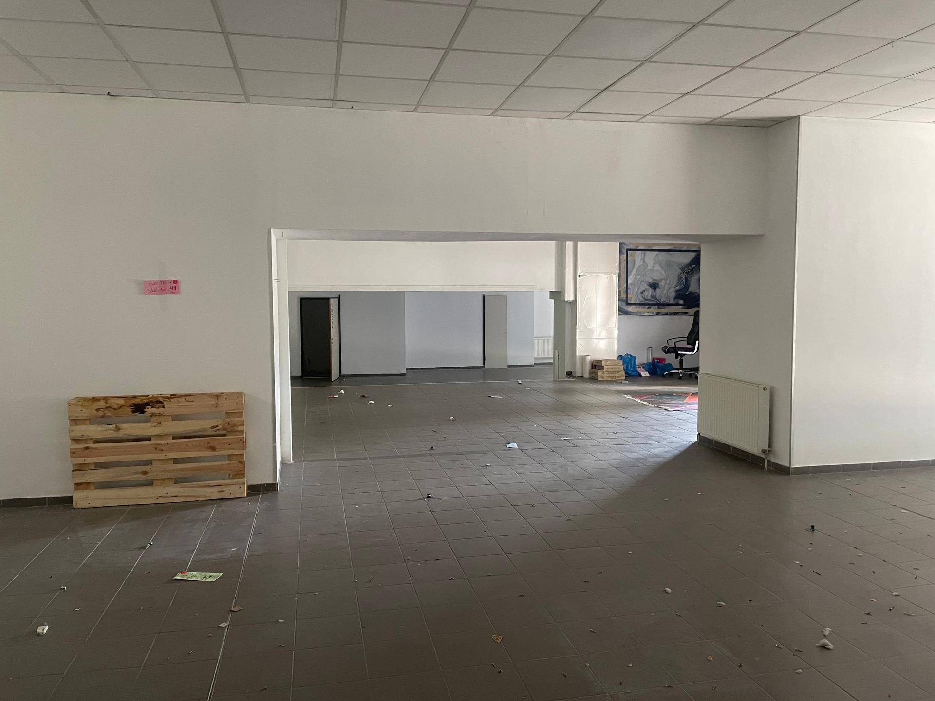 Großer, offener Gewerberaum mit Fliesenboden und Blick in angrenzende Bereiche.