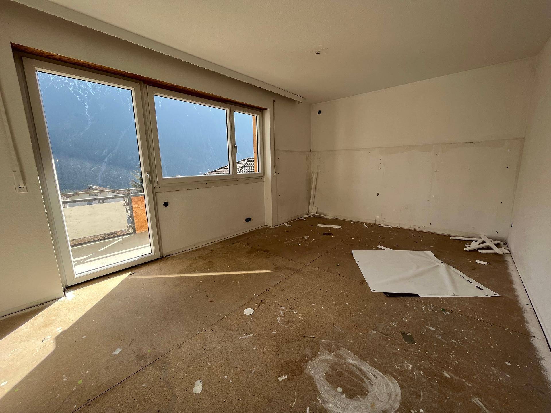 Schlafzimmer mit Zugang zum Balkon und weitem Bergblick, bereit für die Renovierung.