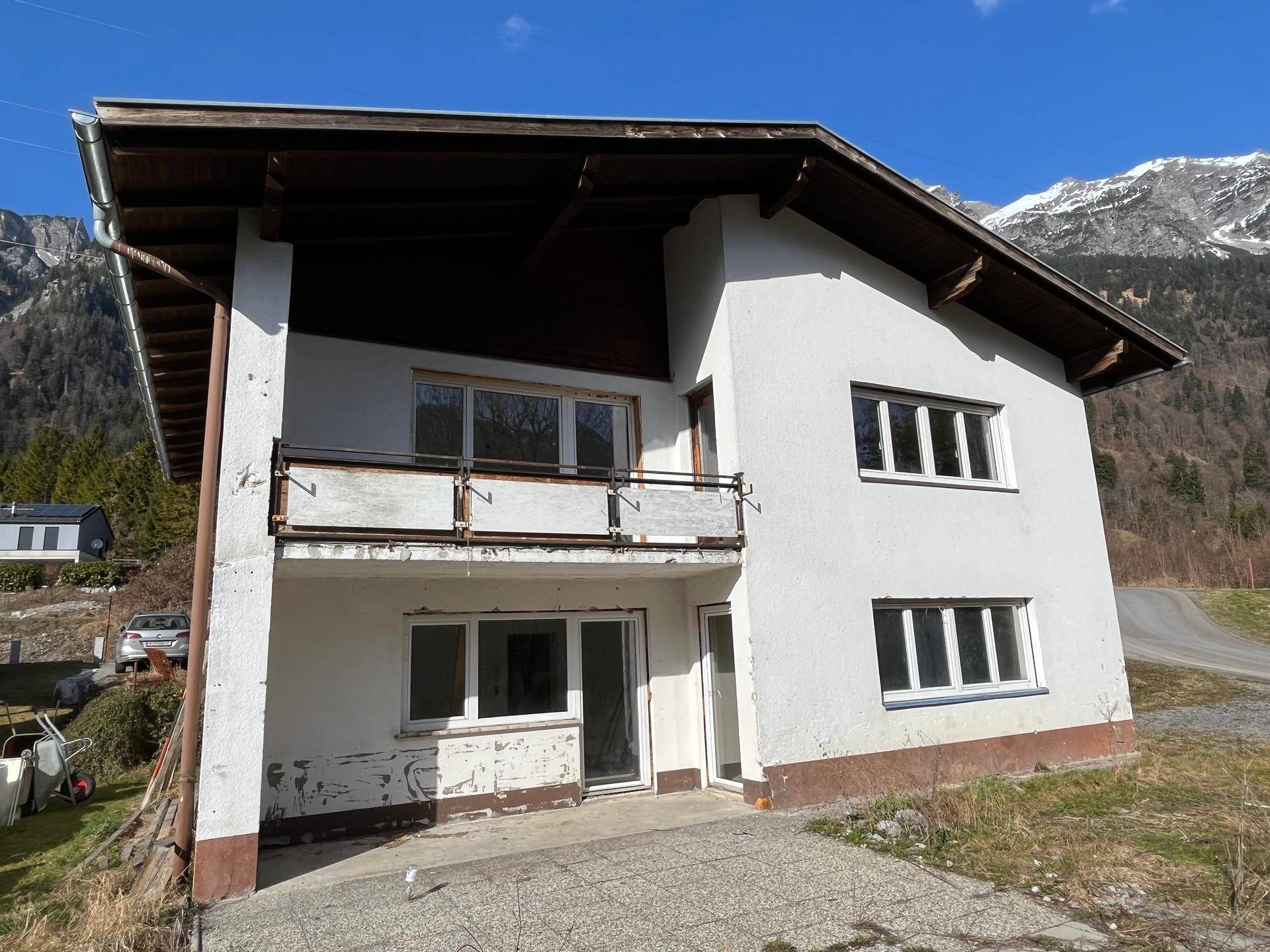 Vorderseite des Hauses mit Balkon und großen Fenstern, bereit für die Renovierung.
