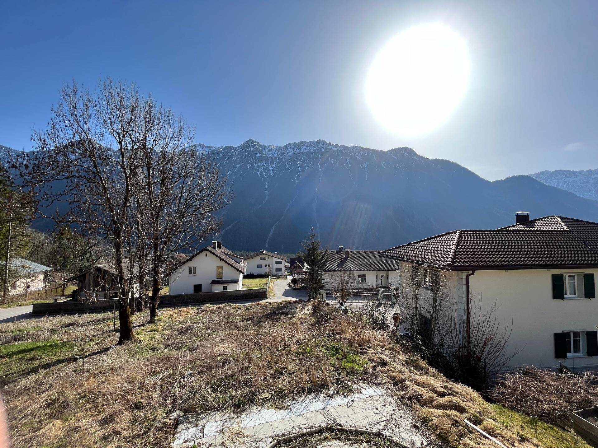 Sonnige Aussicht auf die umliegende Berglandschaft und benachbarte Häuser.