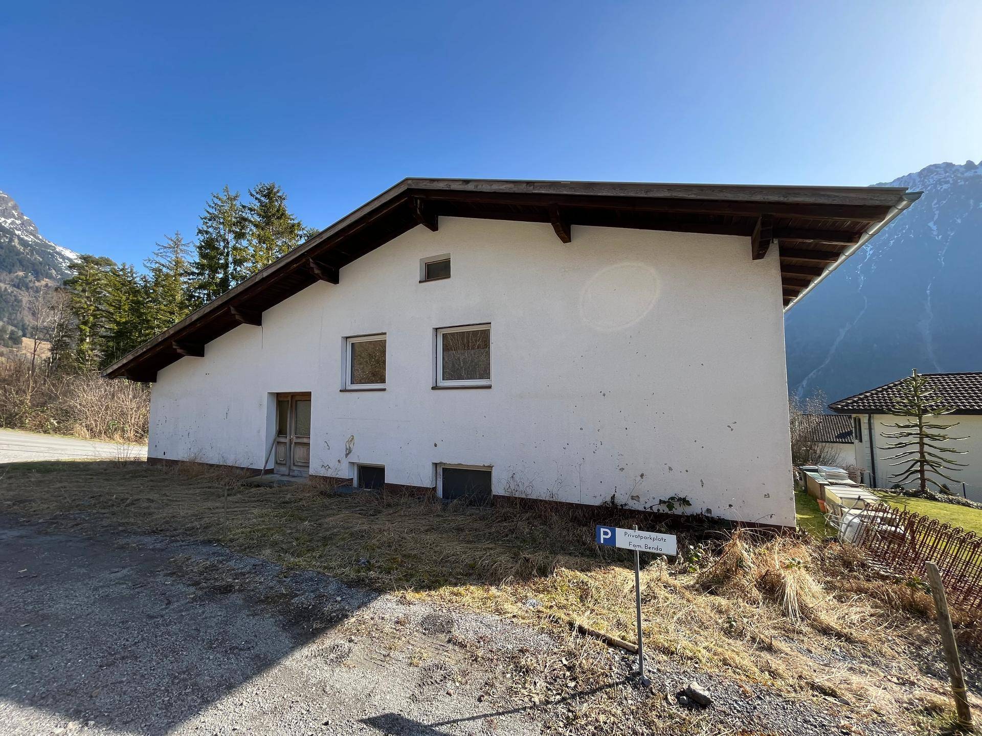 Rückseite des Hauses mit weißer Fassade und Satteldach in ländlicher Umgebung.