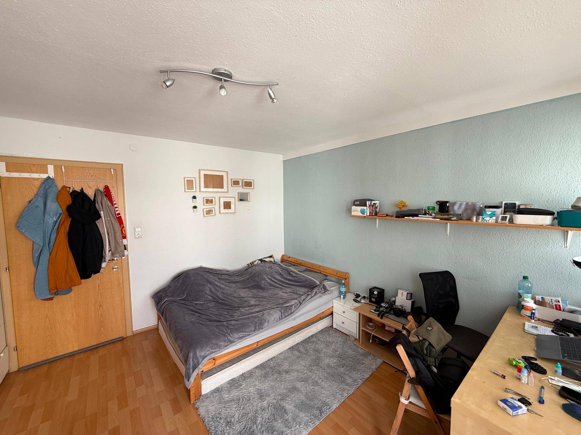 Gemütliches Schlafzimmer mit Holzboden, Bett und einer hellblauen Akzentwand für eine entspannte Atmosphäre.