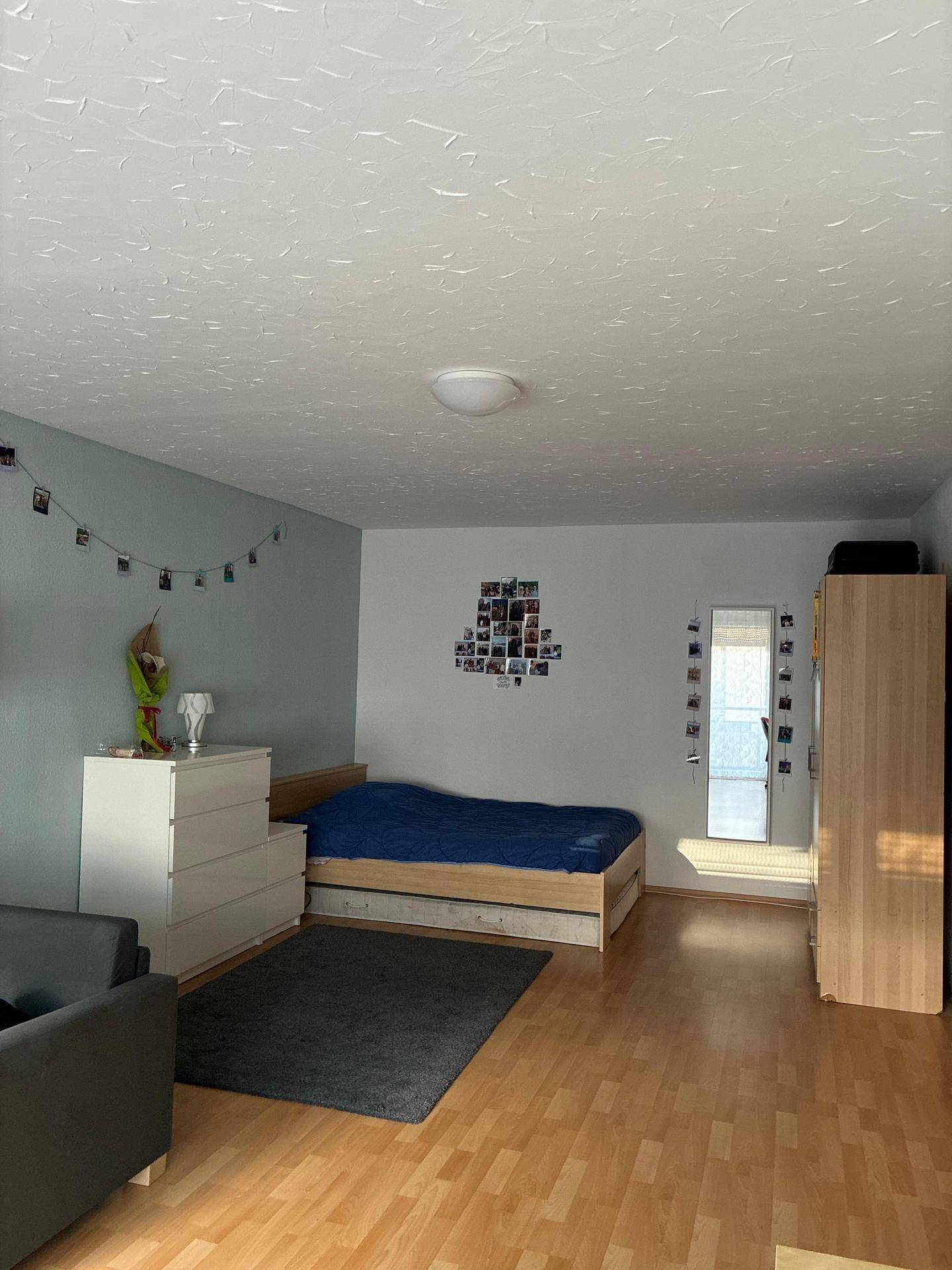 Schlafzimmer mit Holzbett, Kommode und Kleiderschrank, bietet direkten Zugang zum Balkon.
