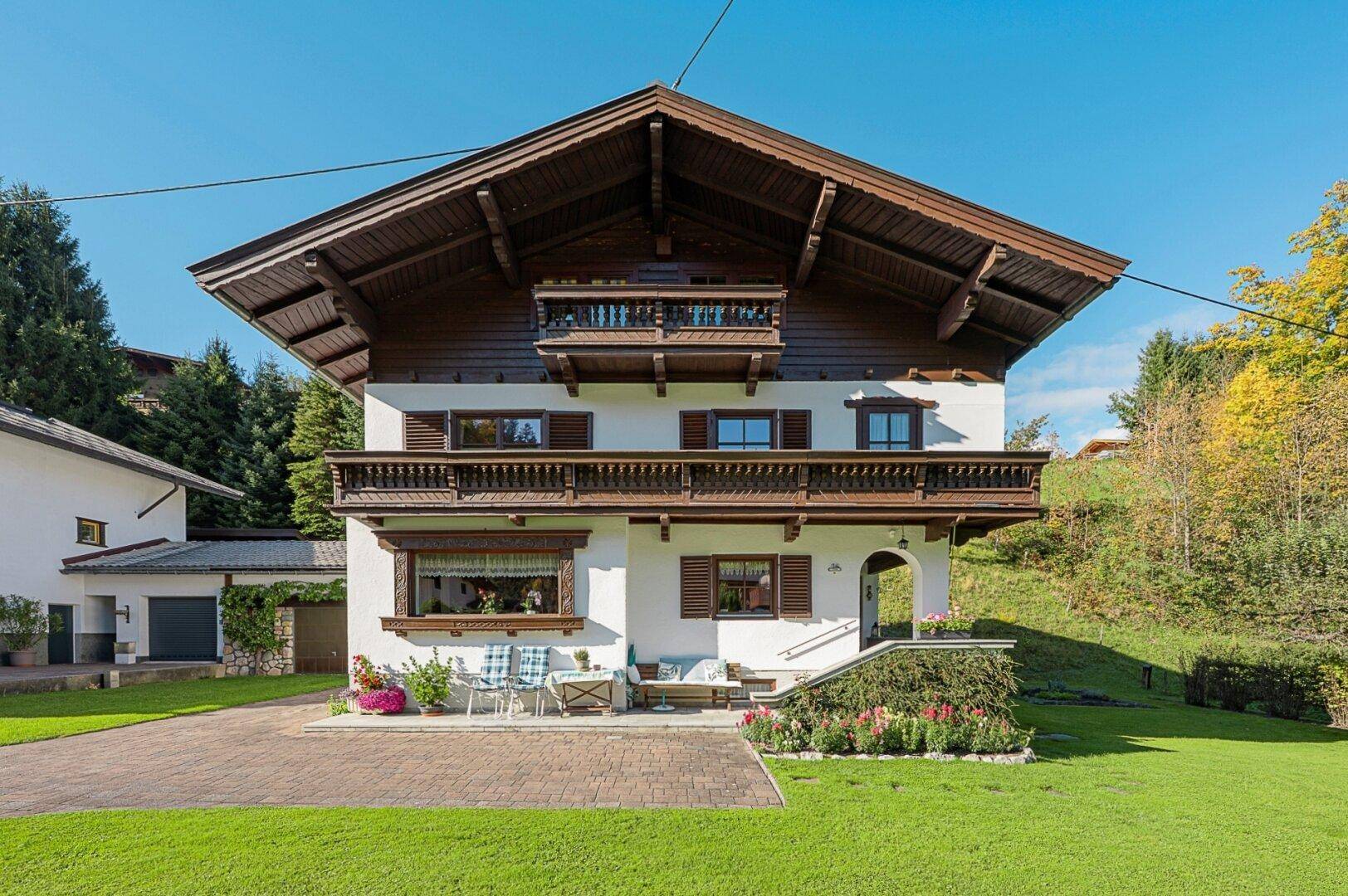 Charmantes Einfamilienhaus mit traditioneller Holzfassade, Balkonen und gepflegtem Vorgarten.
