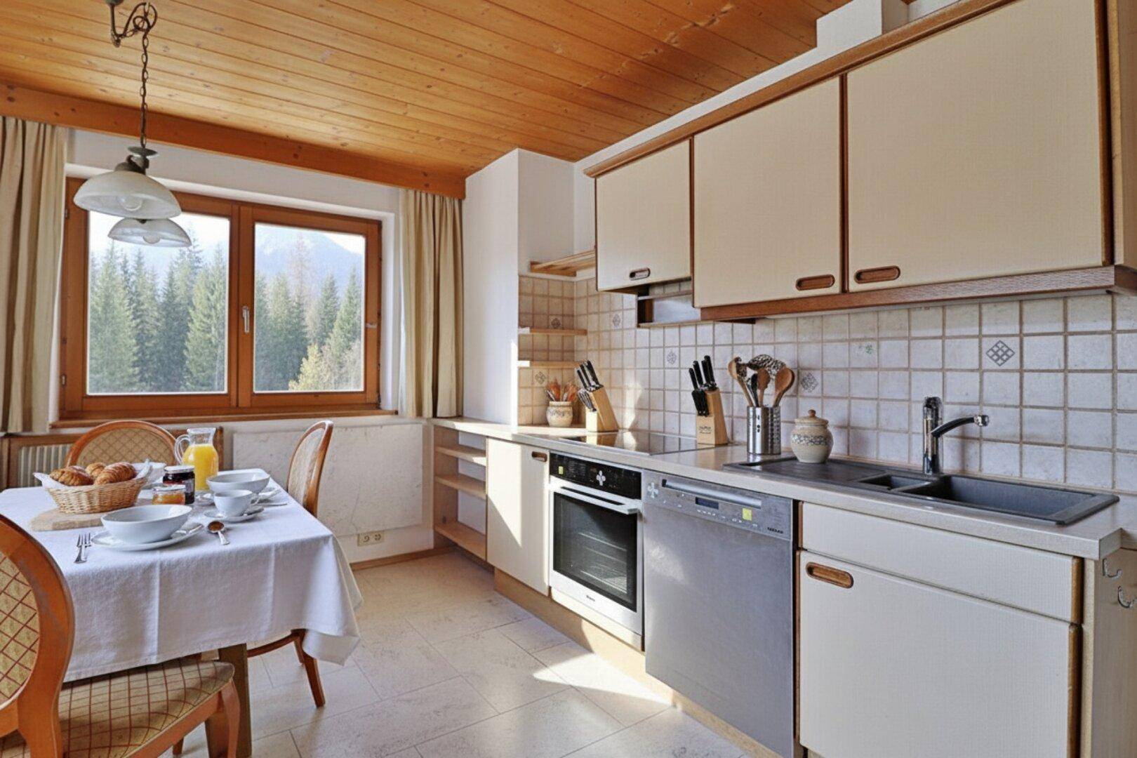 Helle Wohnküche mit Essbereich, Holzdecke und Blick auf die Berge.