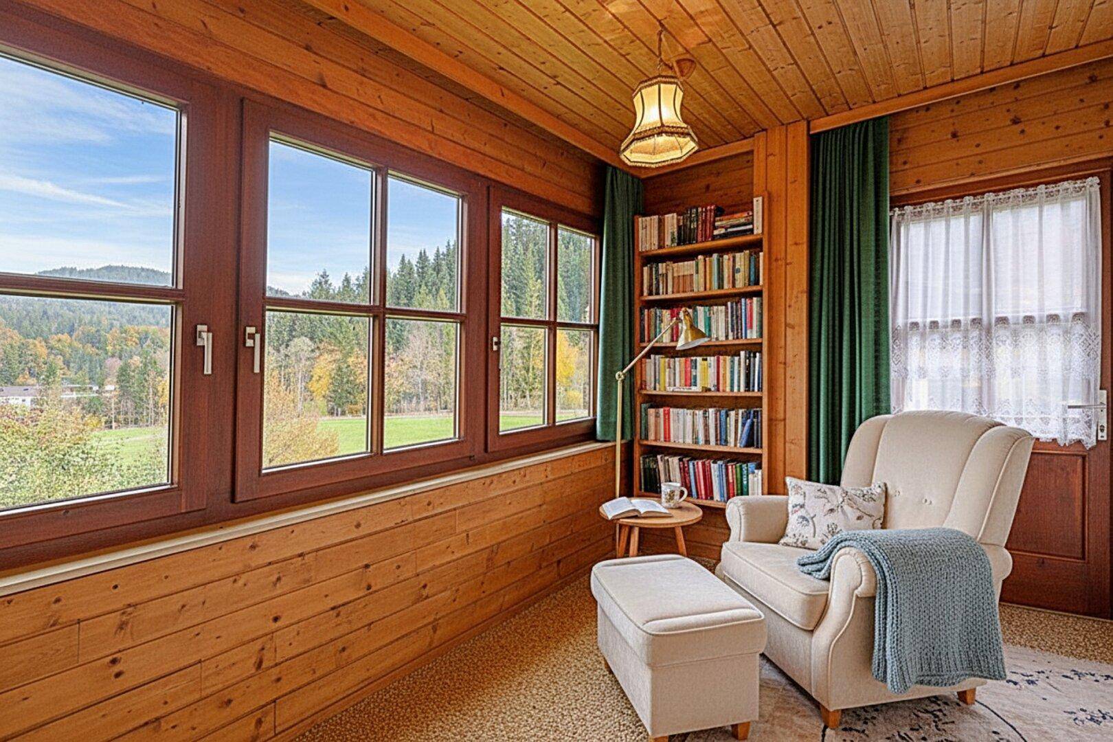 Heller Wintergarten mit Holzvertäfelung, Bücherregal und weitem Blick ins Grüne.