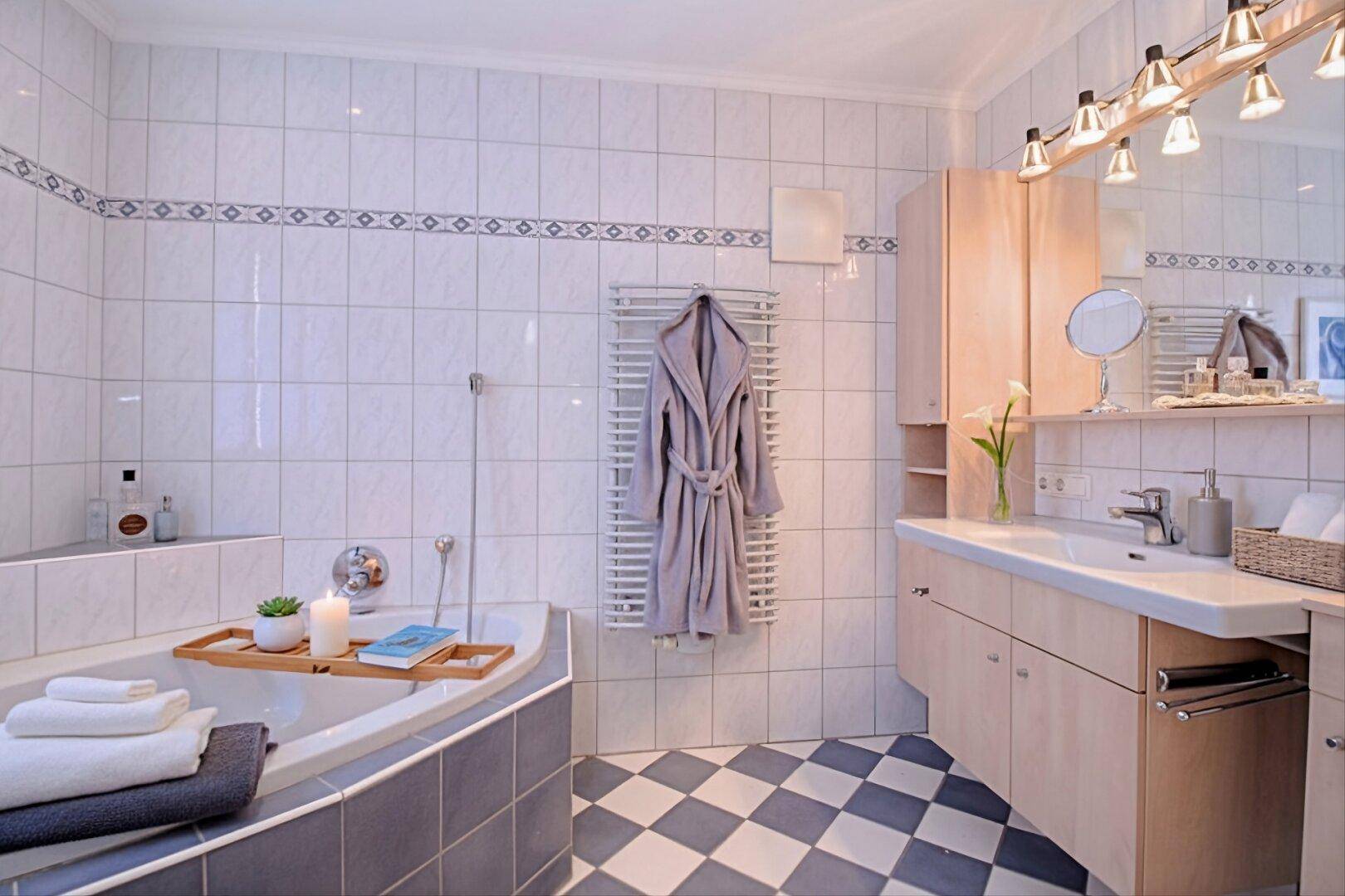 Helles Badezimmer mit Badewanne, Waschtisch und weiß-blau kariertem Fliesenboden.