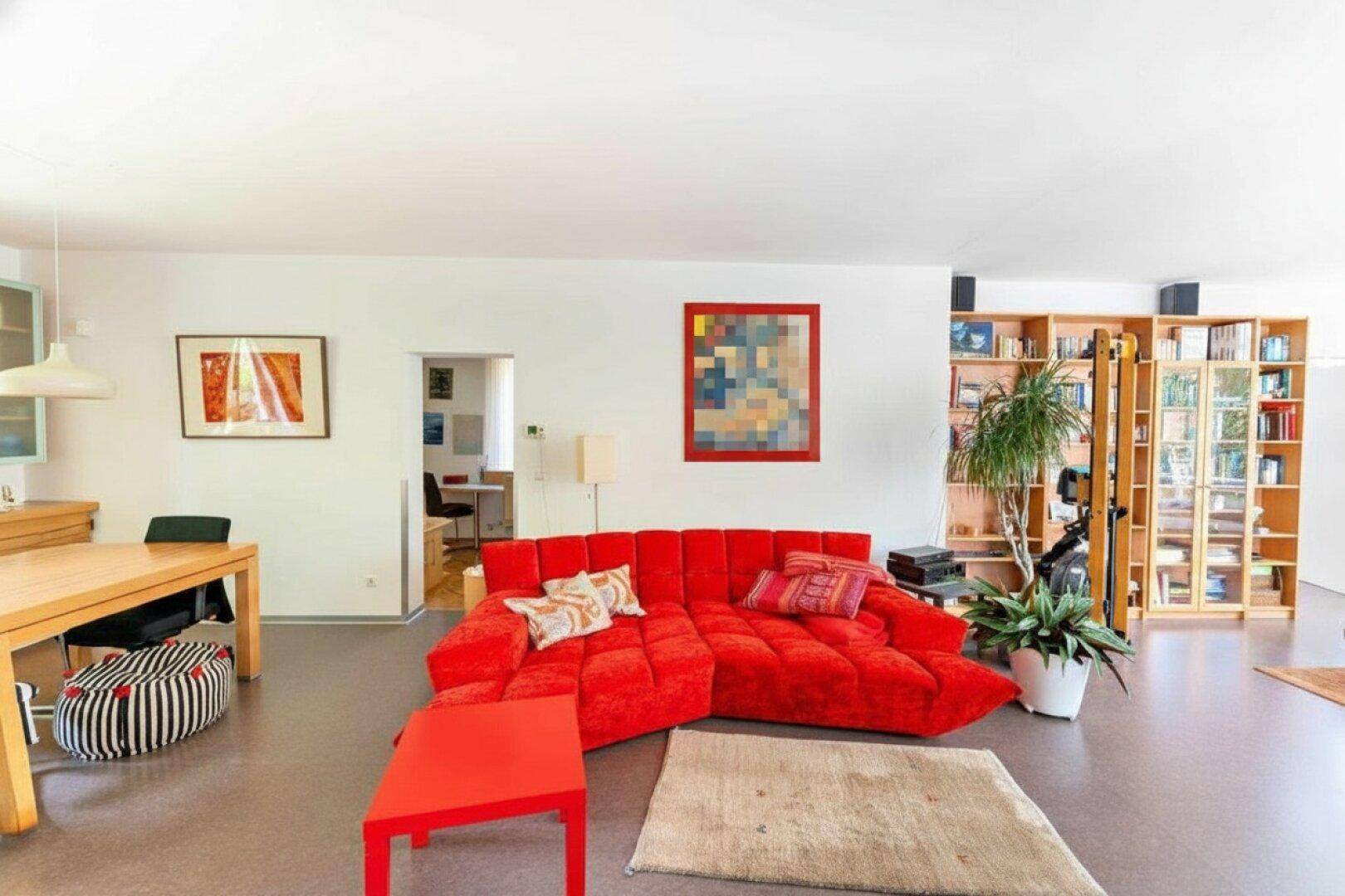 Großzügiger Wohnbereich mit auffälligem rotem Sofa, integrierten Bücherregalen und viel Platz.