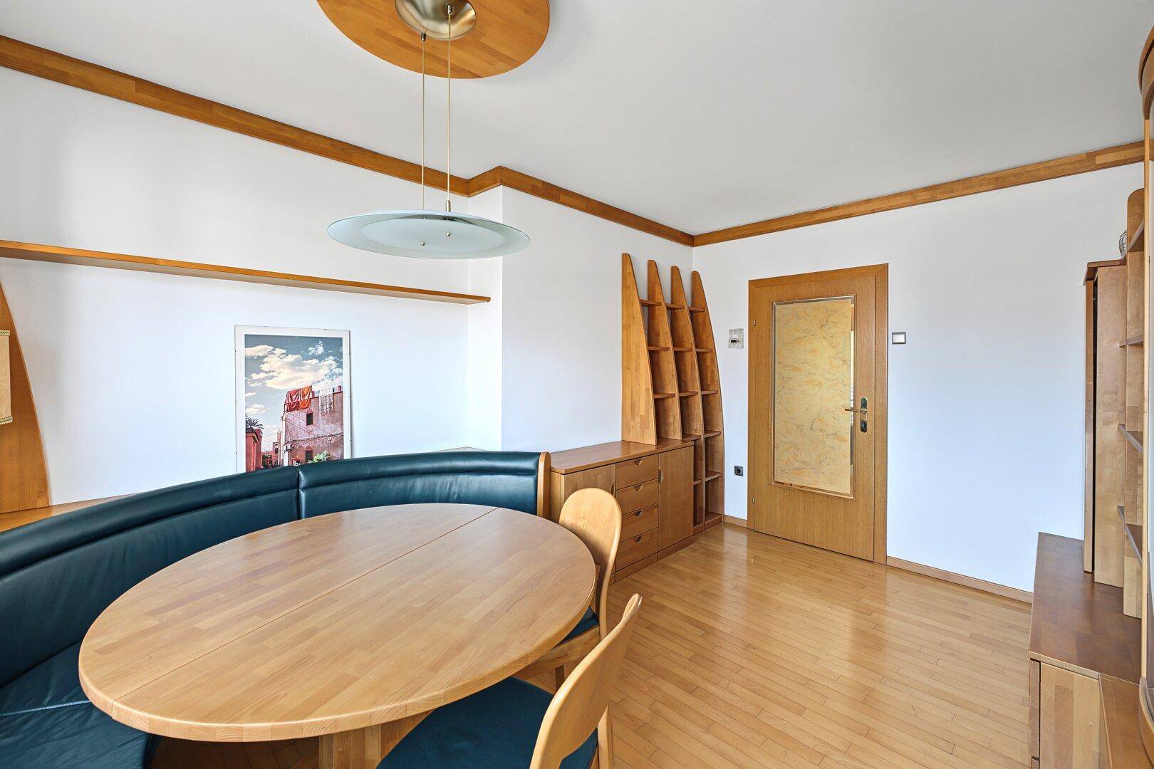 Esszimmer mit ovalem Holztisch, eingebauter Sitzbank und Holzregalen.