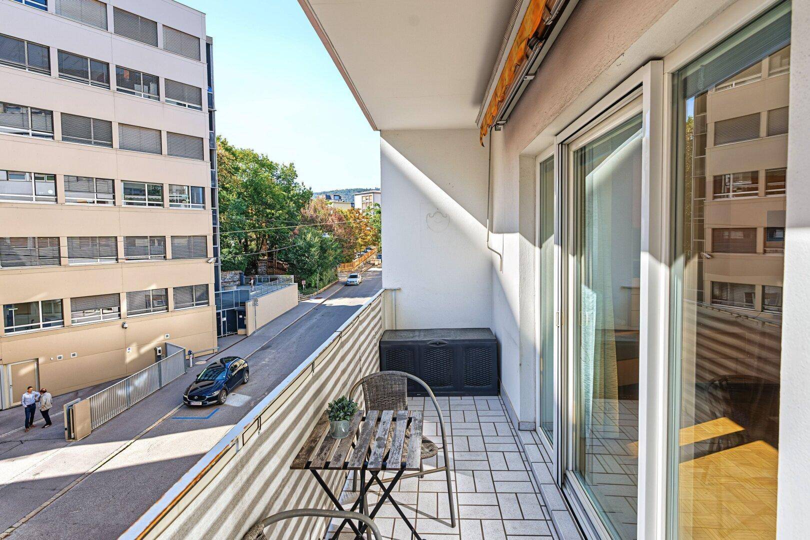 Möblierter Balkon mit Fliesenboden und Blick auf die umliegenden Gebäude.