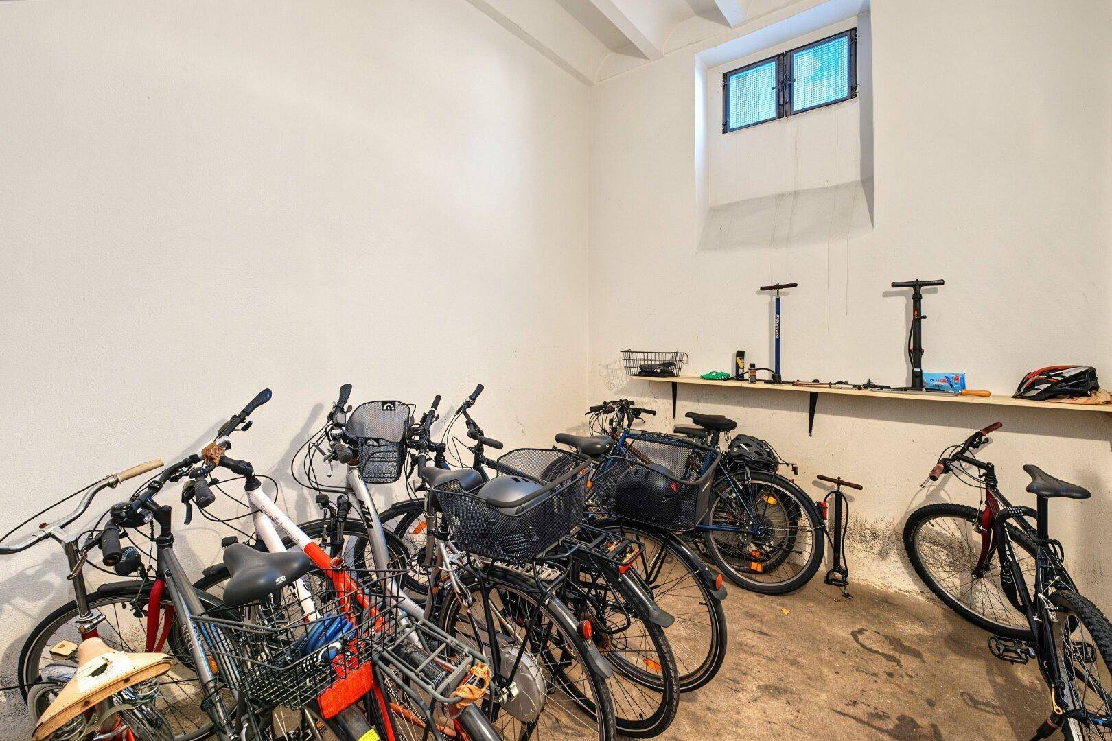 Fahrradraum mit mehreren Fahrrädern, Werkzeugablage und kleinem Fenster.