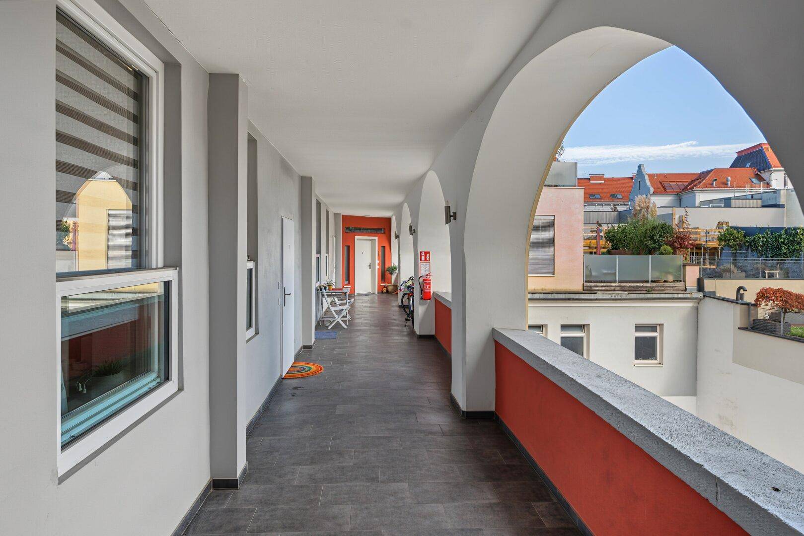 Überdachter Außenflur mit Bögen und Blick auf die umliegenden Gebäude.