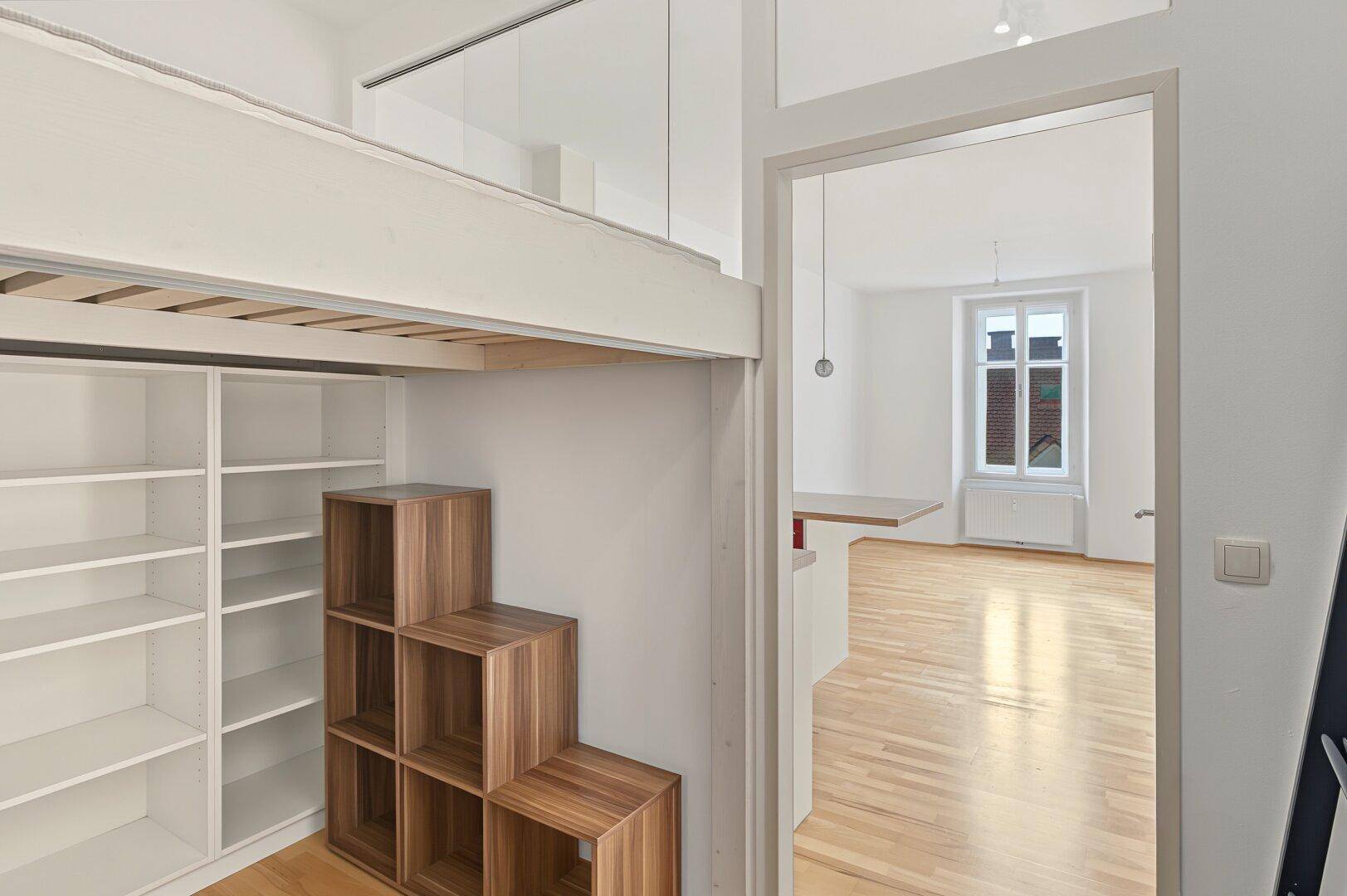 Schlafbereich mit Hochbett, integrierten Regalen und Blick in den Wohnraum.