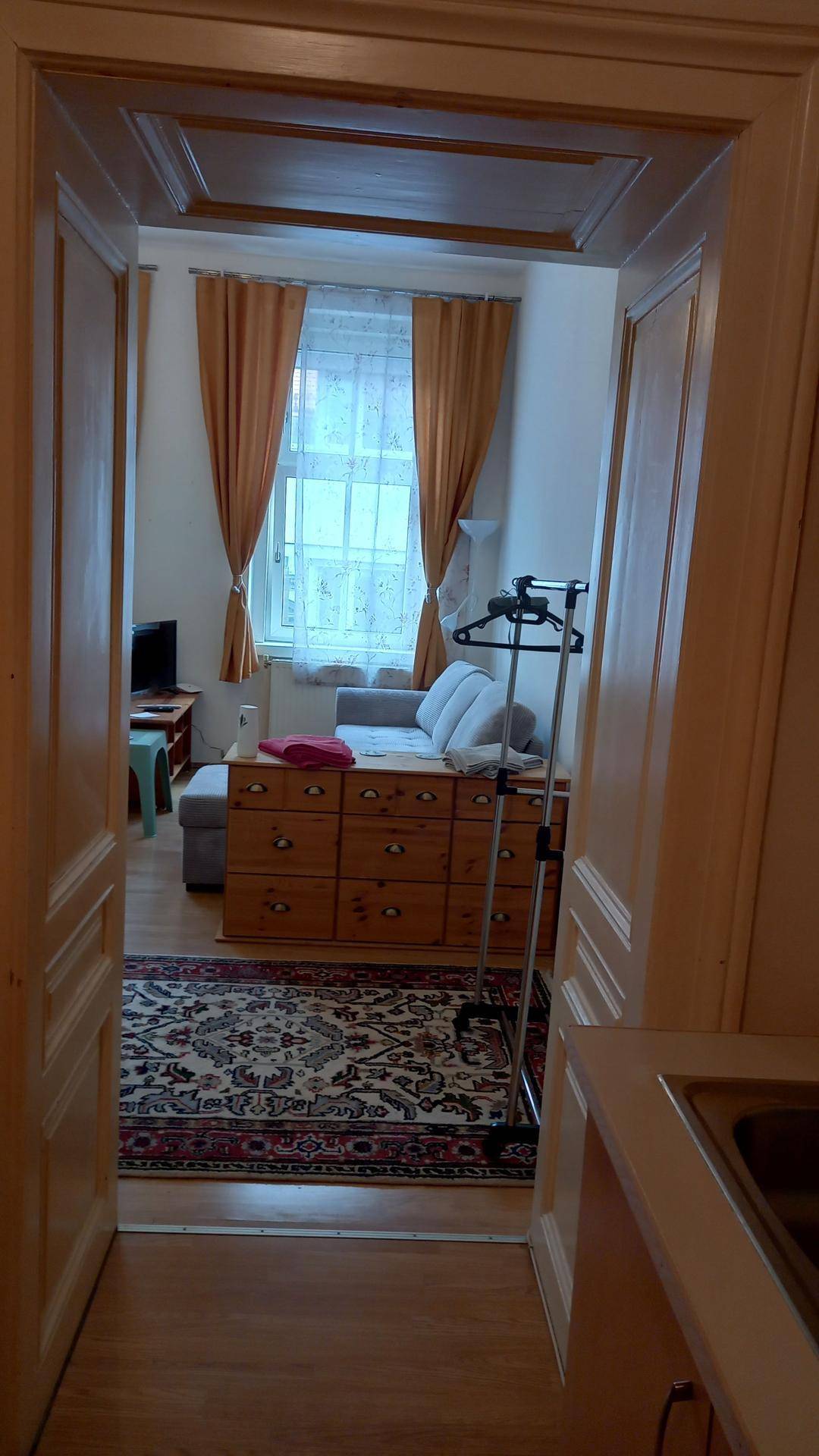 Blick durch die Tür vom Küchenbereich in den Wohn- und Essbereich mit Sofa und Fenstern.