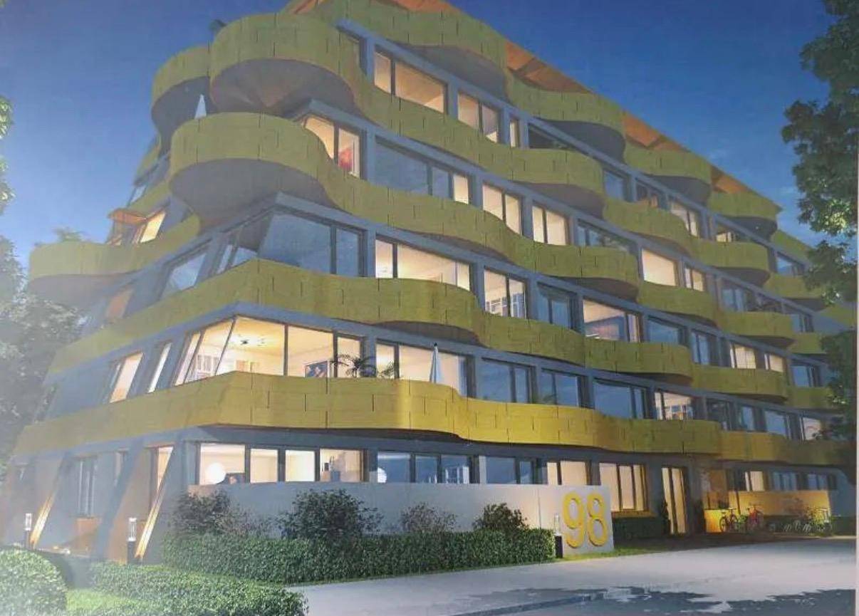 Moderne Architektur mit auffälliger gelber Fassade und großen Fensterfronten.