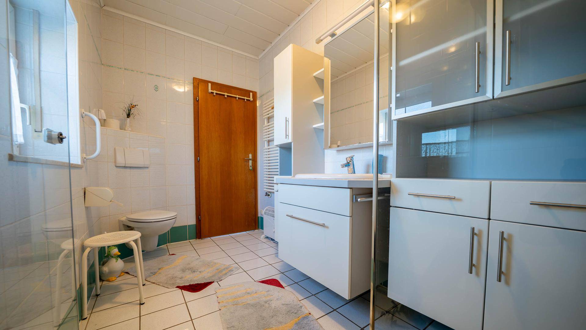 Helles Badezimmer mit Dusche, WC, Waschbecken und praktischen Schränken.