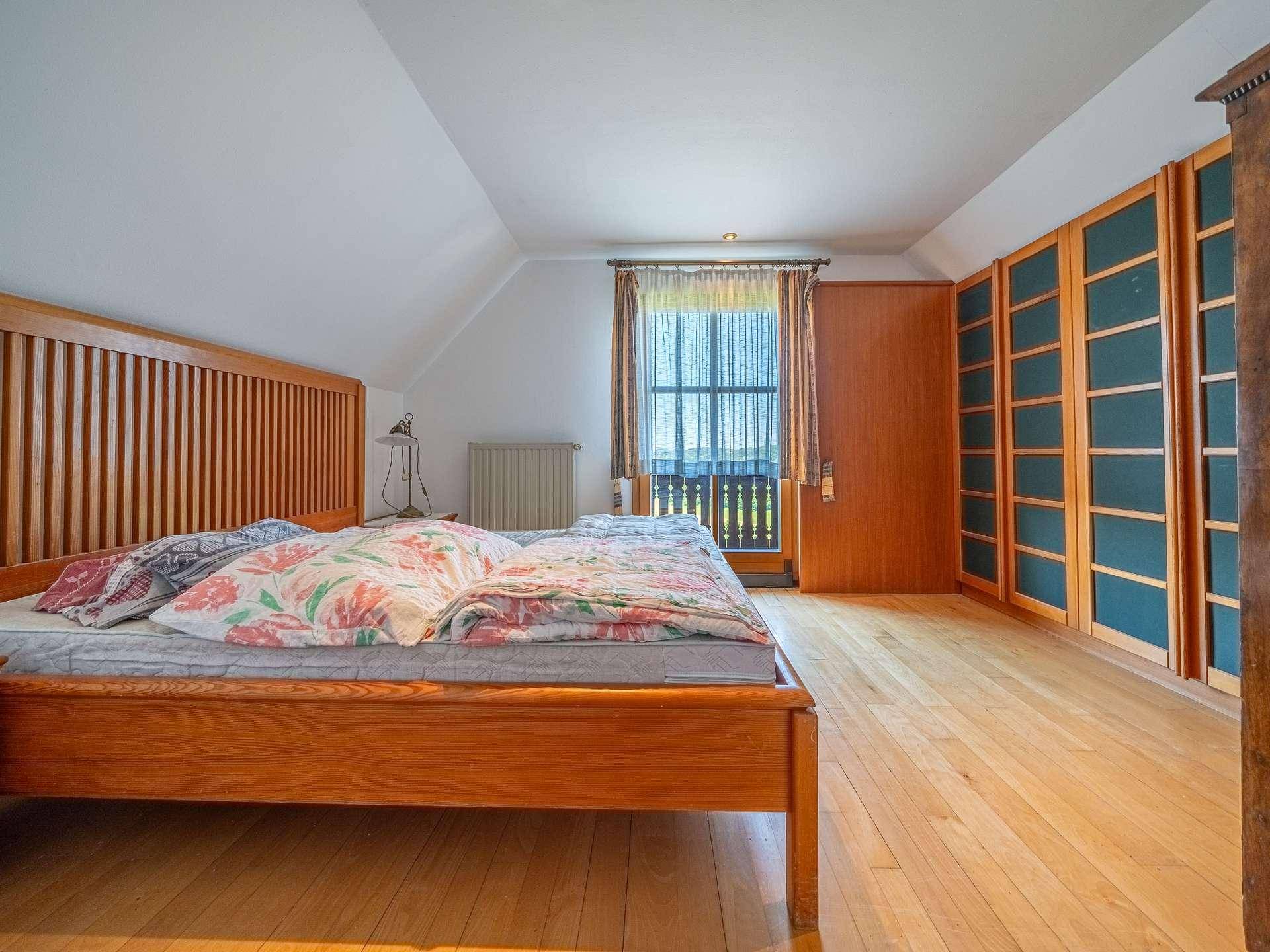 Gemütliches Schlafzimmer mit Holzboden, Zugang zum Balkon und traditionellen Holzmöbeln.