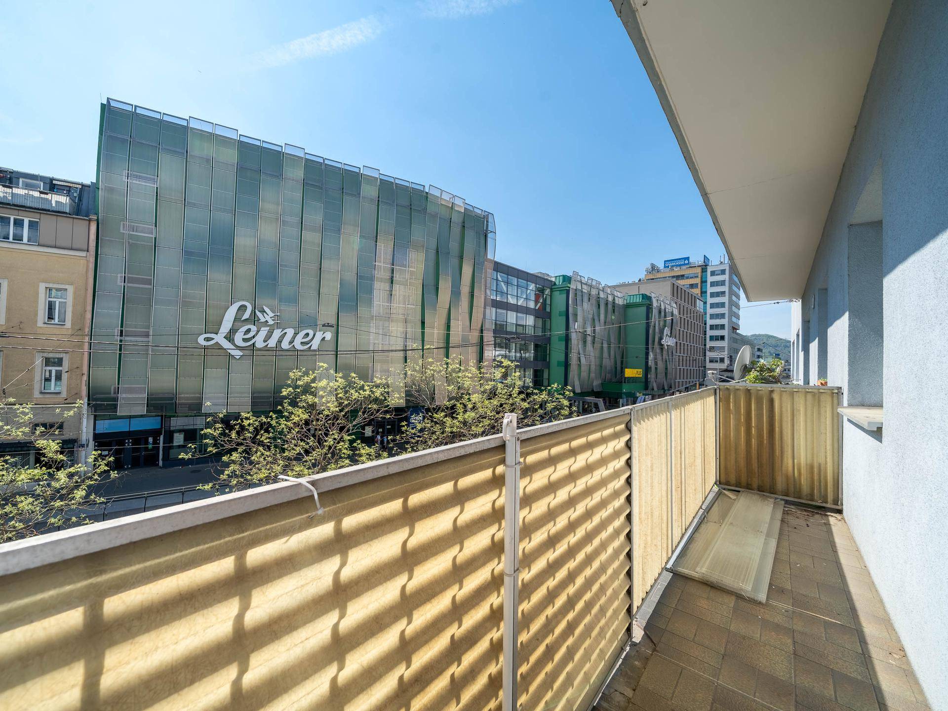 Balkon mit Blick auf ein großes Einkaufszentrum und die Stadt.