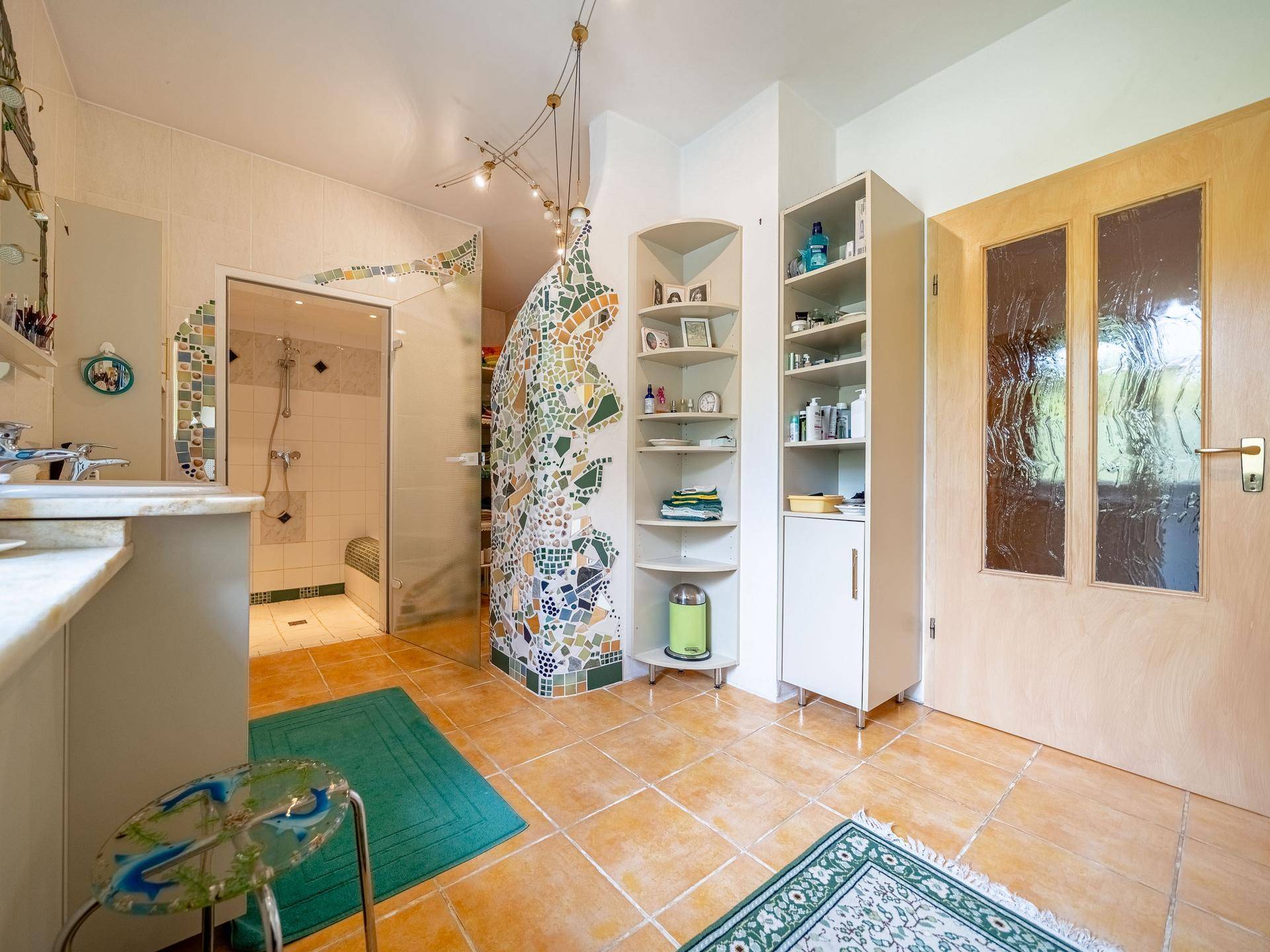 Badezimmer mit farbenfroher Mosaikwand, Fliesenboden und begehbarer Dusche.