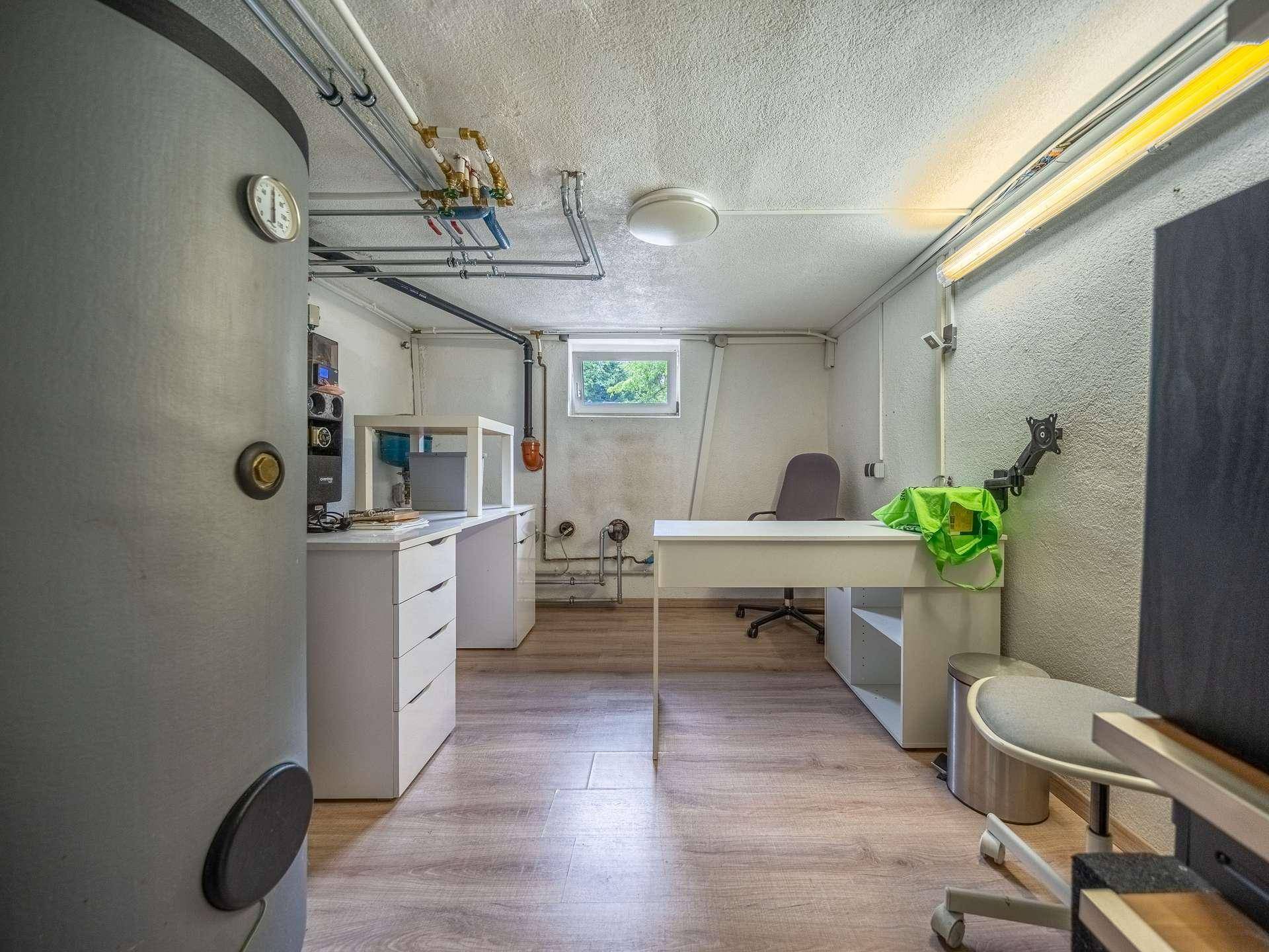 Funktionaler Kellerraum mit Heizungsanlage, Arbeitsbereich und kleinem Fenster.
