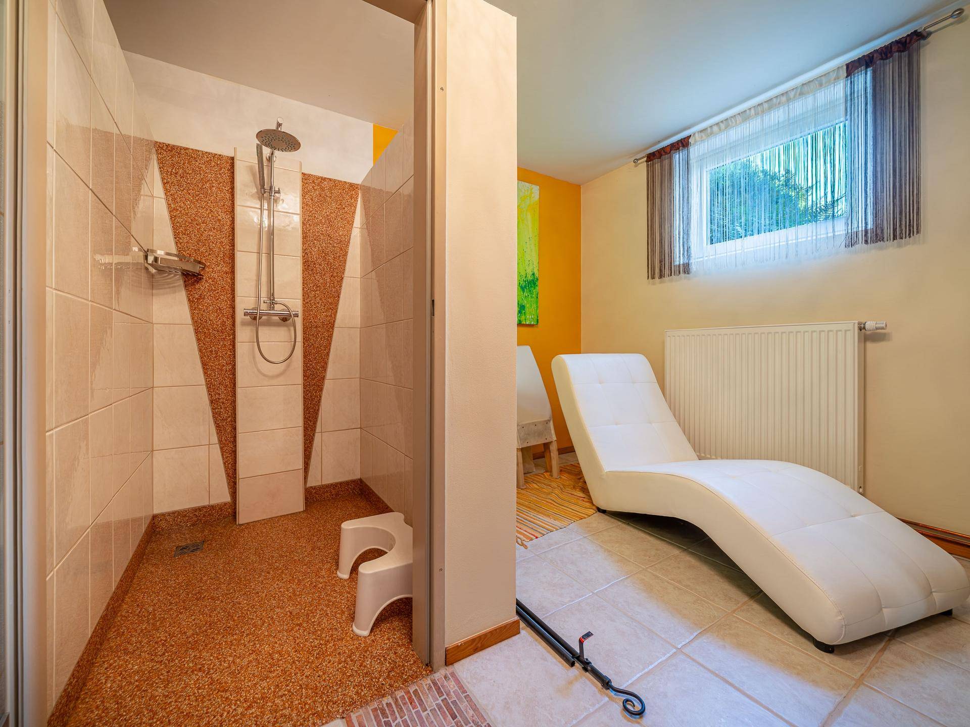 Wellnessbereich mit begehbarer Dusche und einer bequemen Liege zum Entspannen.