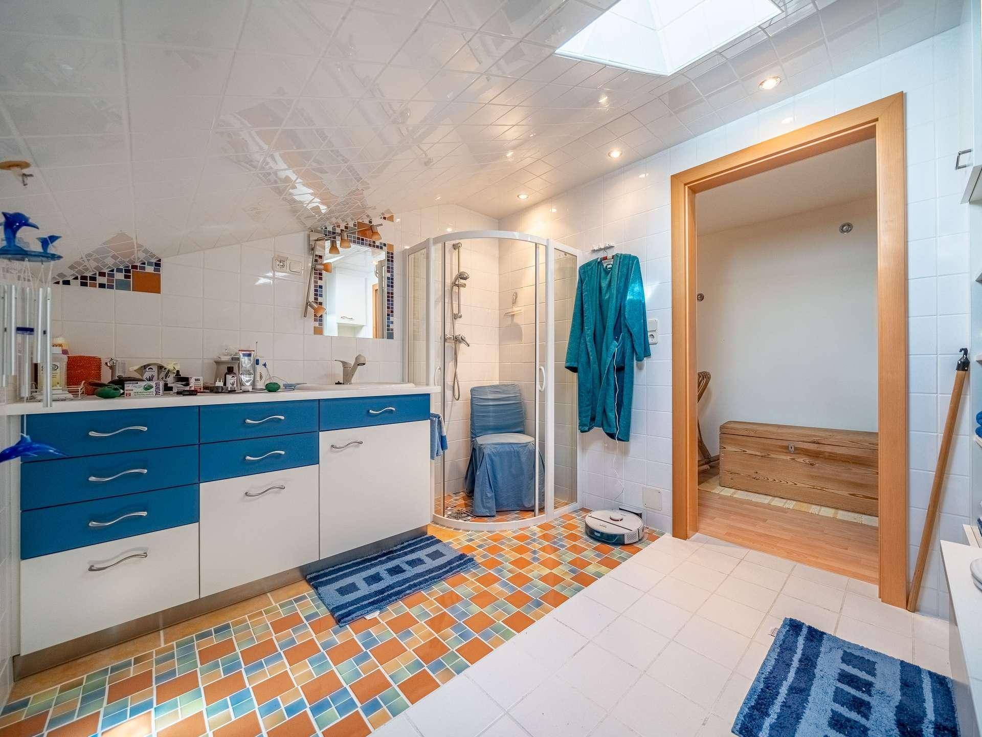 Geräumiges Badezimmer mit Duschkabine, farbigen Fliesen und Dachfenster für natürliches Licht.