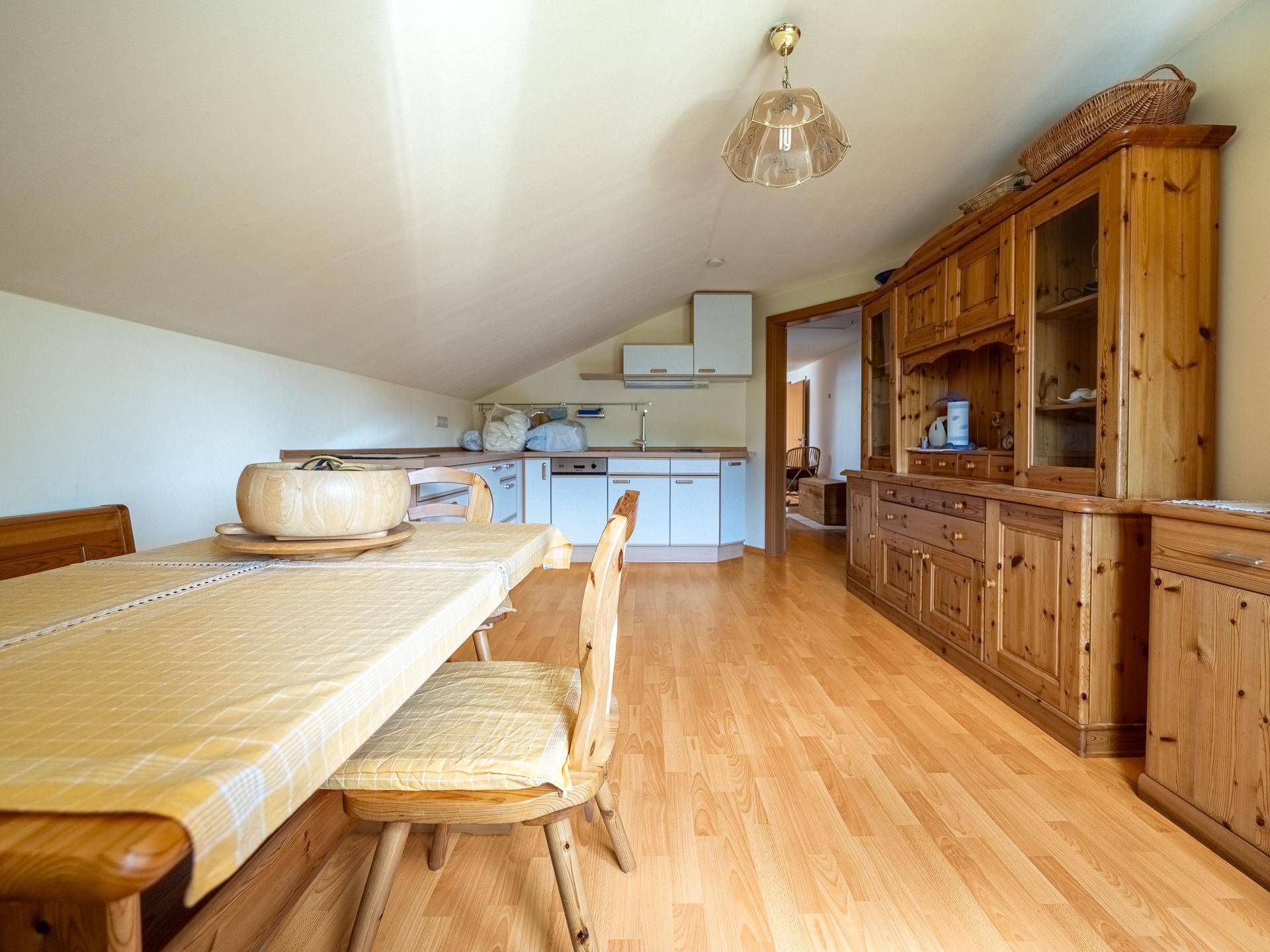 Dachgeschossküche mit Essbereich, Holzmöbeln und Laminatboden.