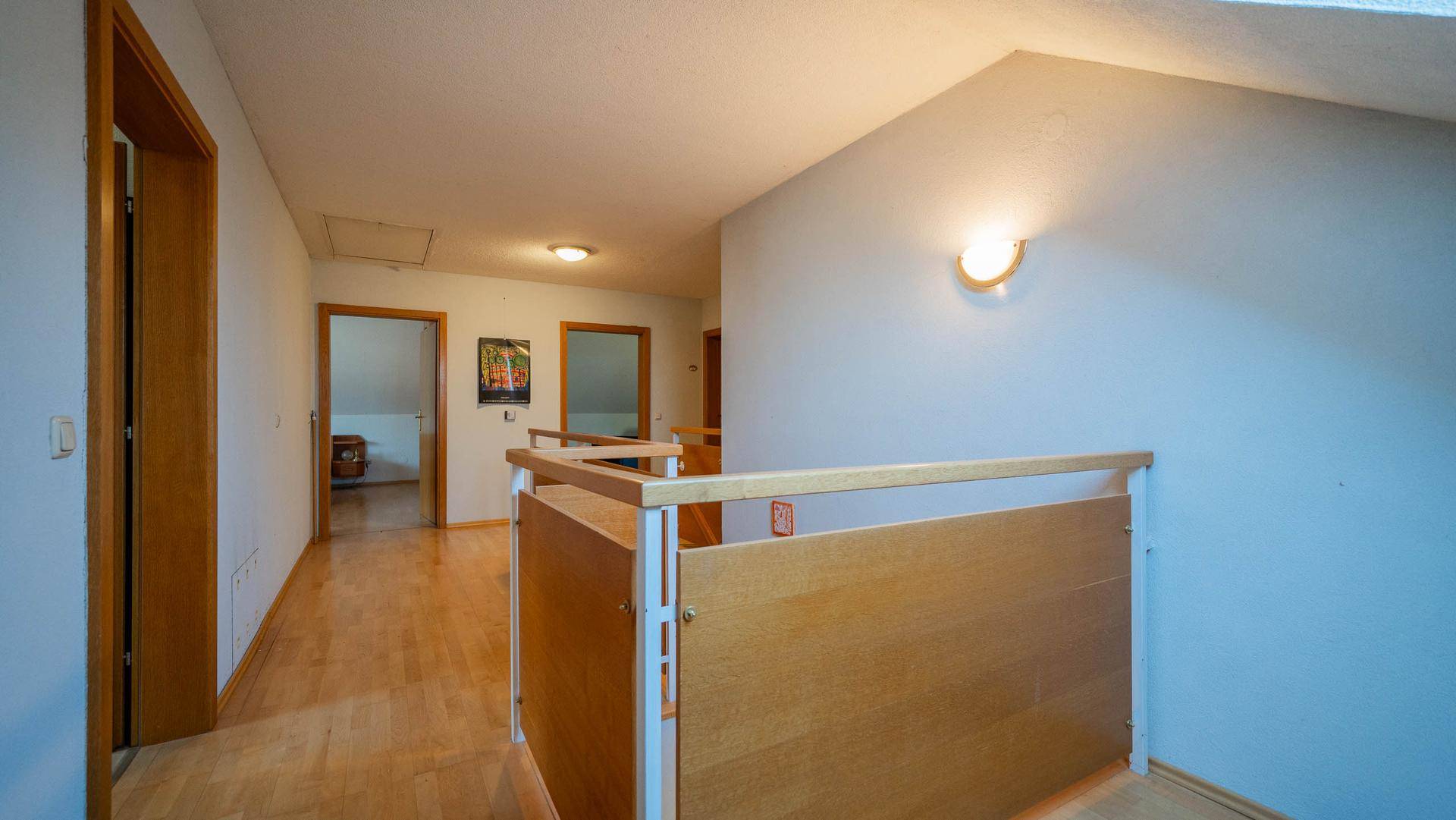 Flur im Obergeschoss mit Holzboden, Dachschräge und Zugang zu weiteren Zimmern.