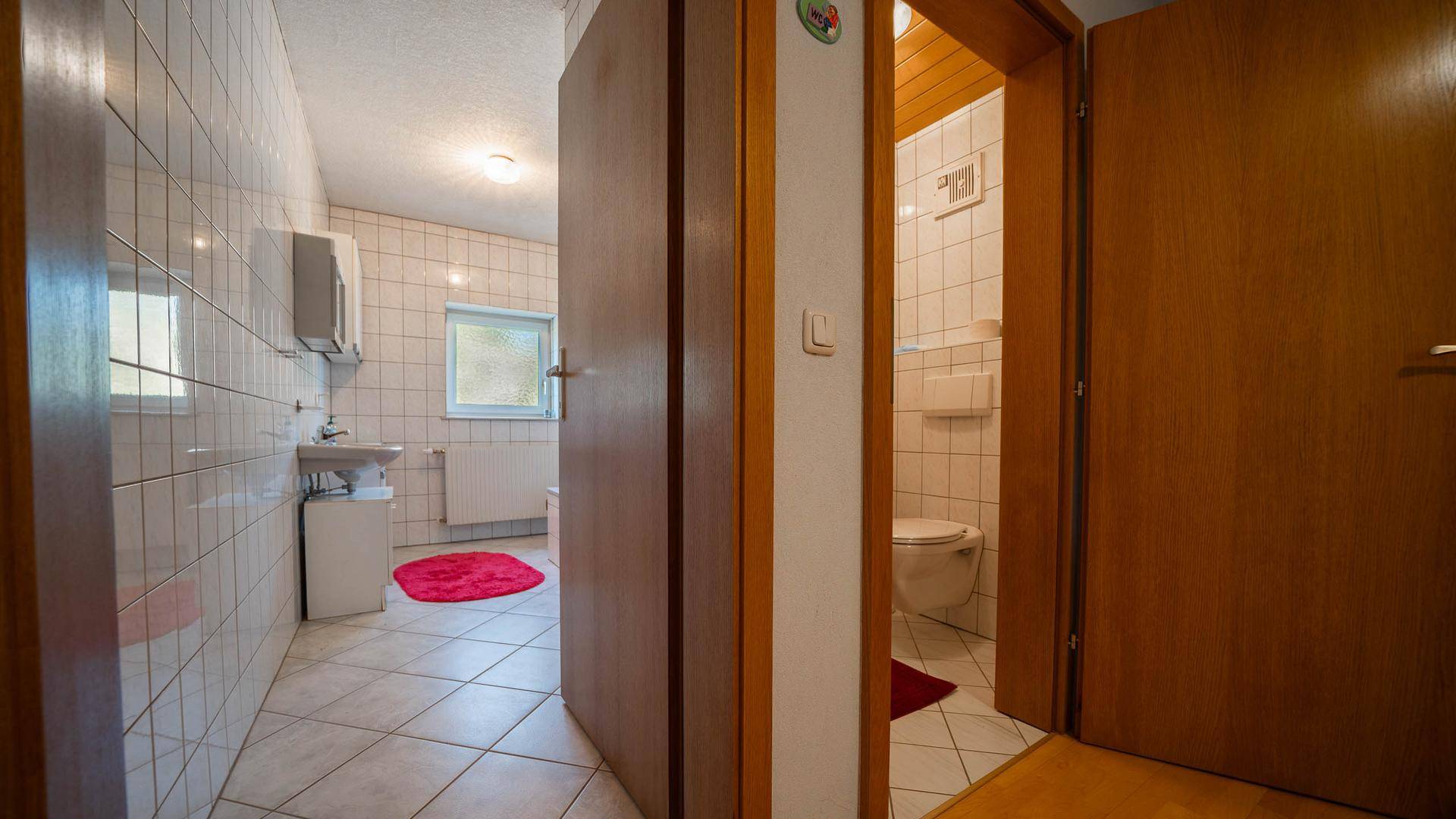Badezimmer mit Badewanne, Waschbecken und separatem WC-Bereich.