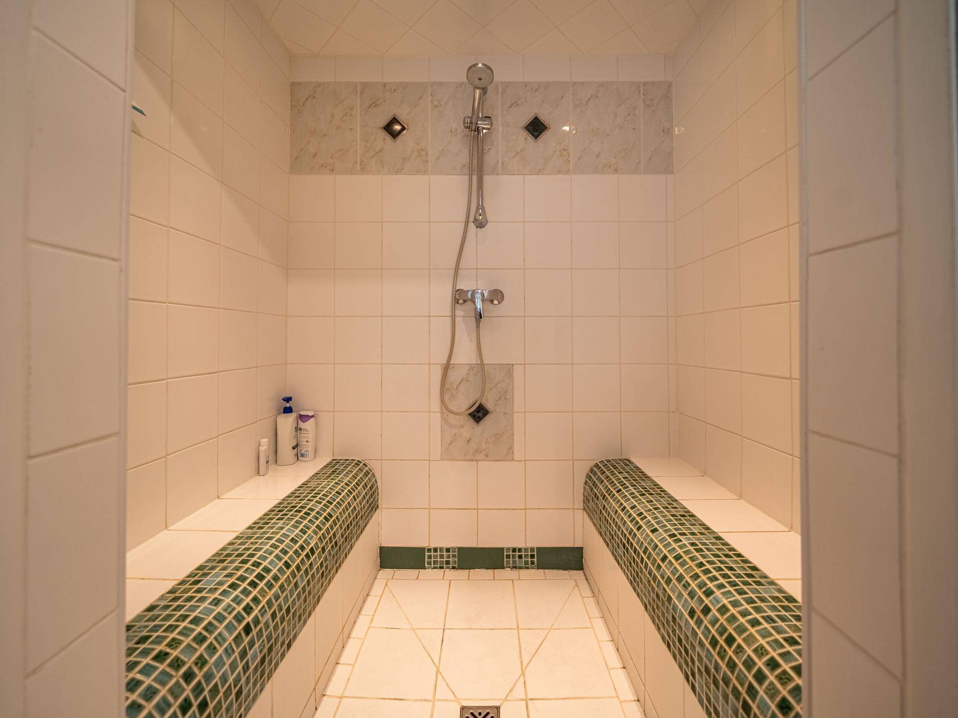Geräumige begehbare Dusche mit Sitzgelegenheiten und modernen Fliesen.