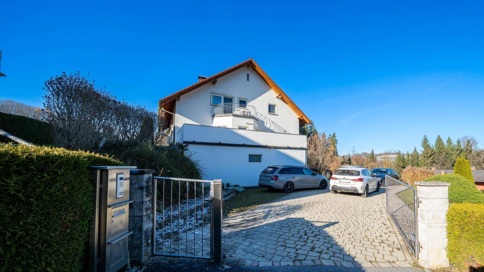 Zufahrt zum Haus mit gepflastertem Bereich und mehreren Parkplätzen.