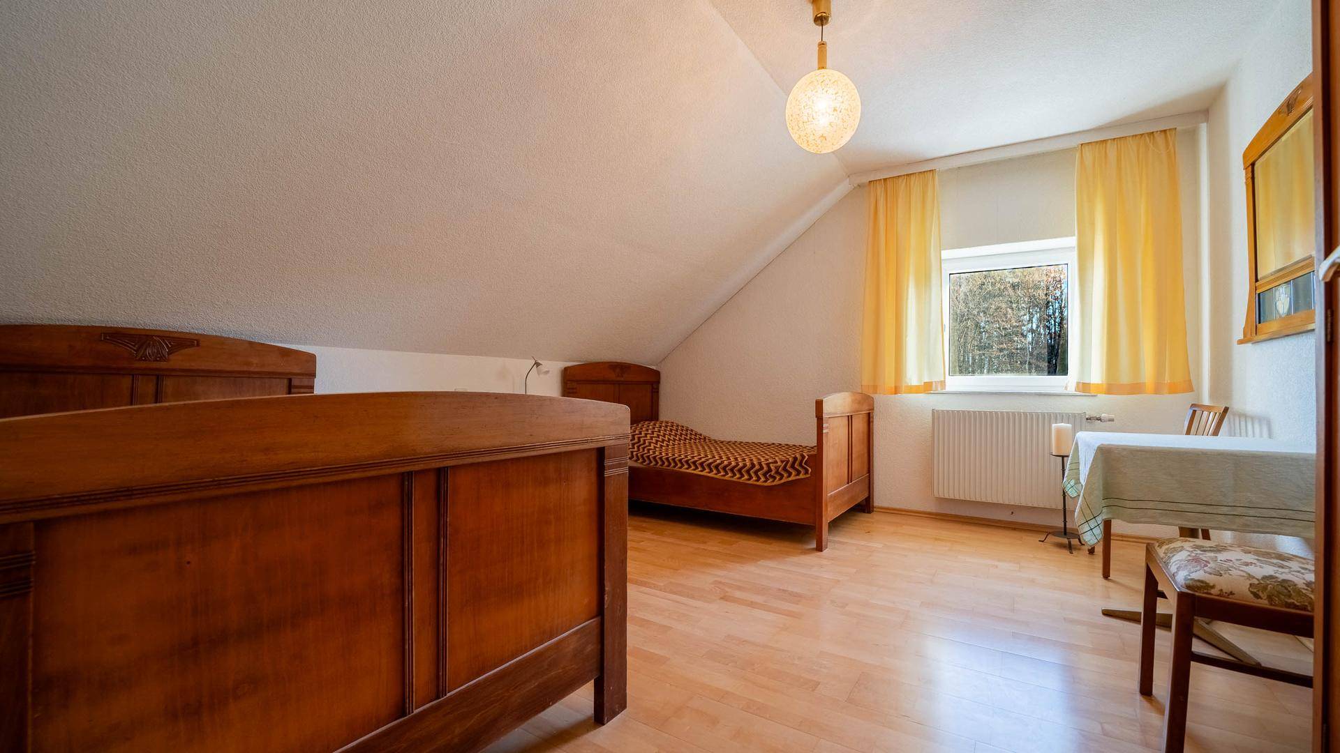Schlafzimmer im Dachgeschoss mit Holzboden, Dachschräge und zwei Einzelbetten.