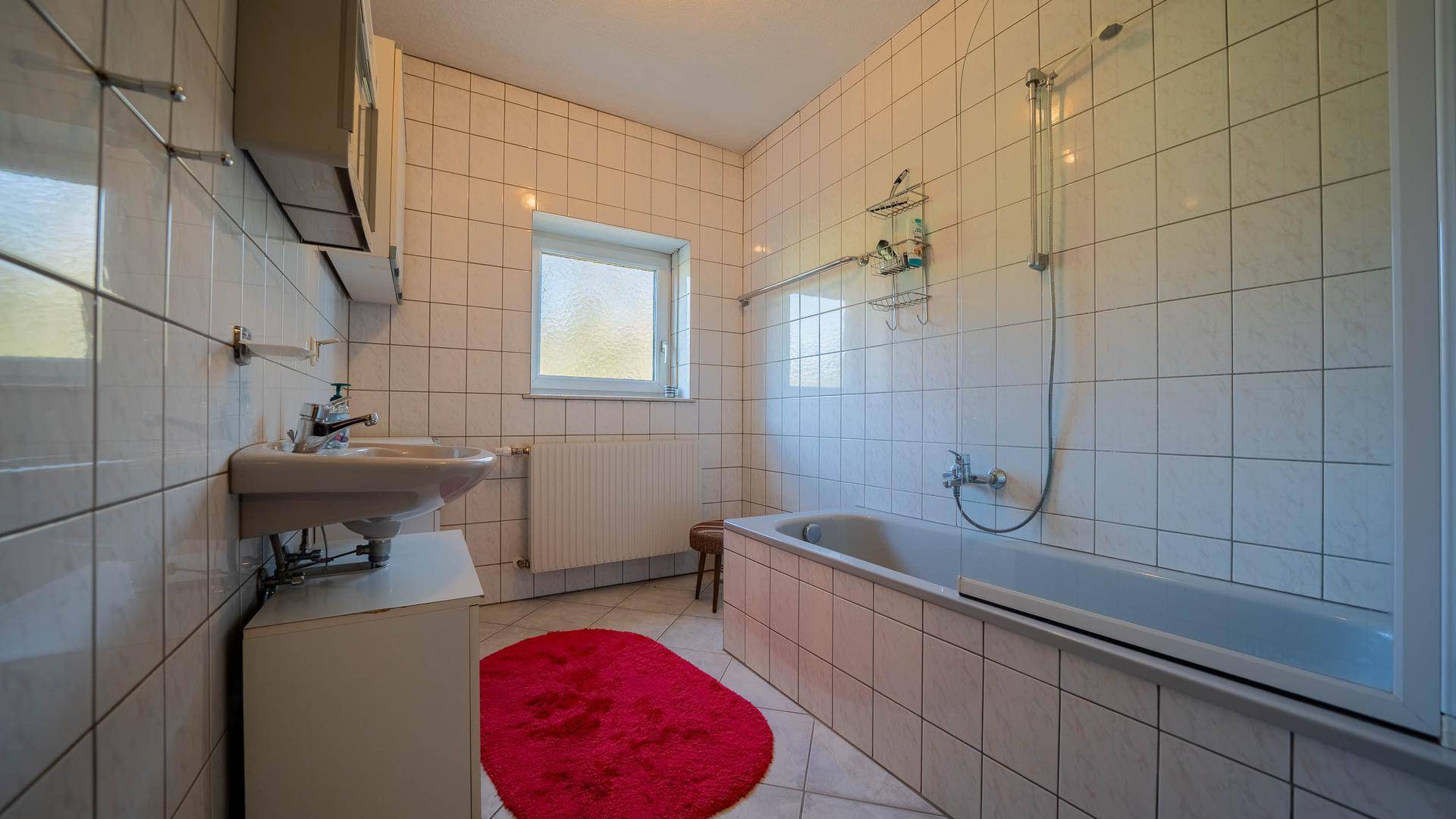 Helles Badezimmer mit Badewanne, Waschbecken, WC und Fenster für natürliche Belüftung.