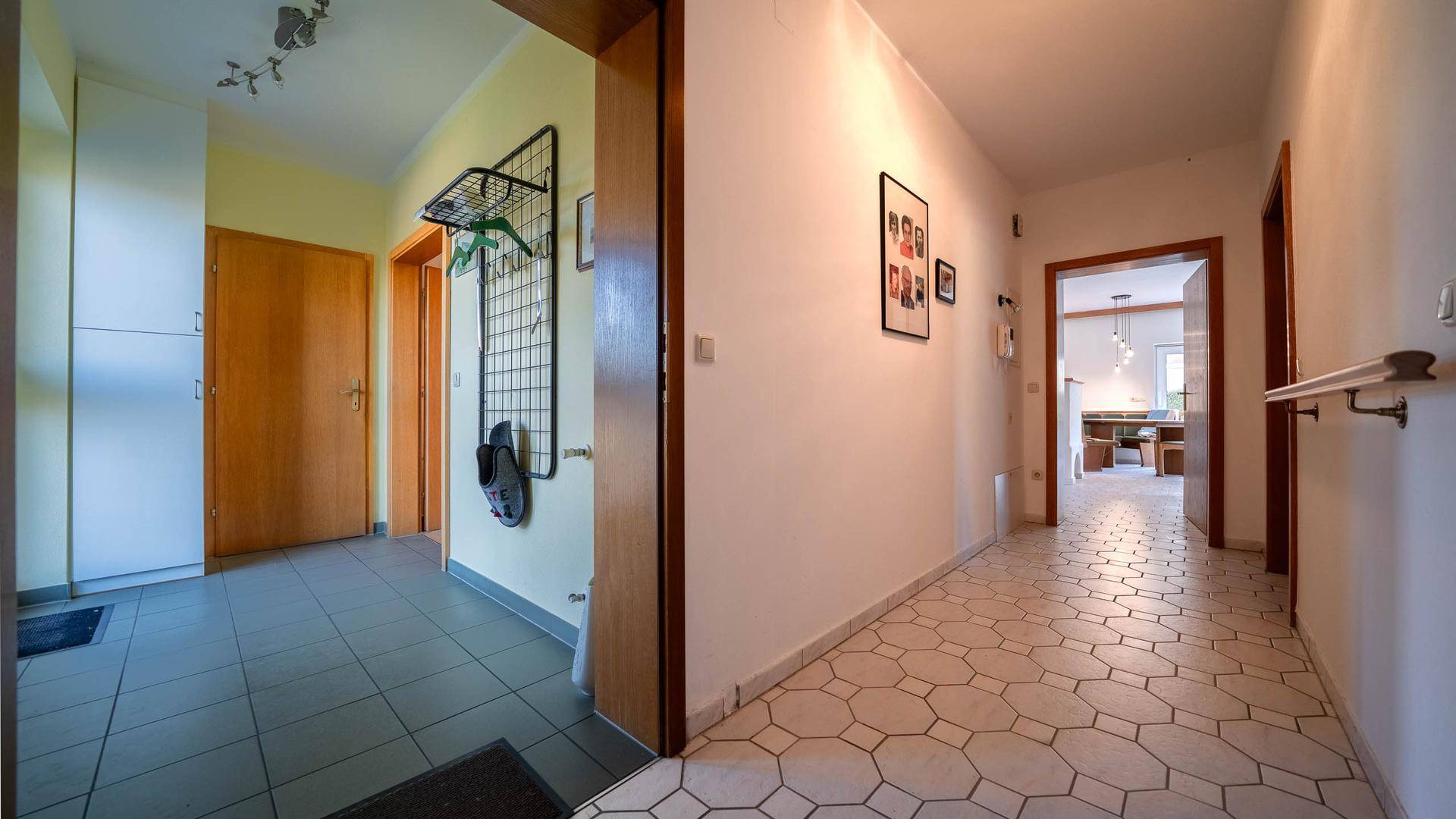Langer Flur mit Fliesenboden, Garderobe und hellem Anstrich.