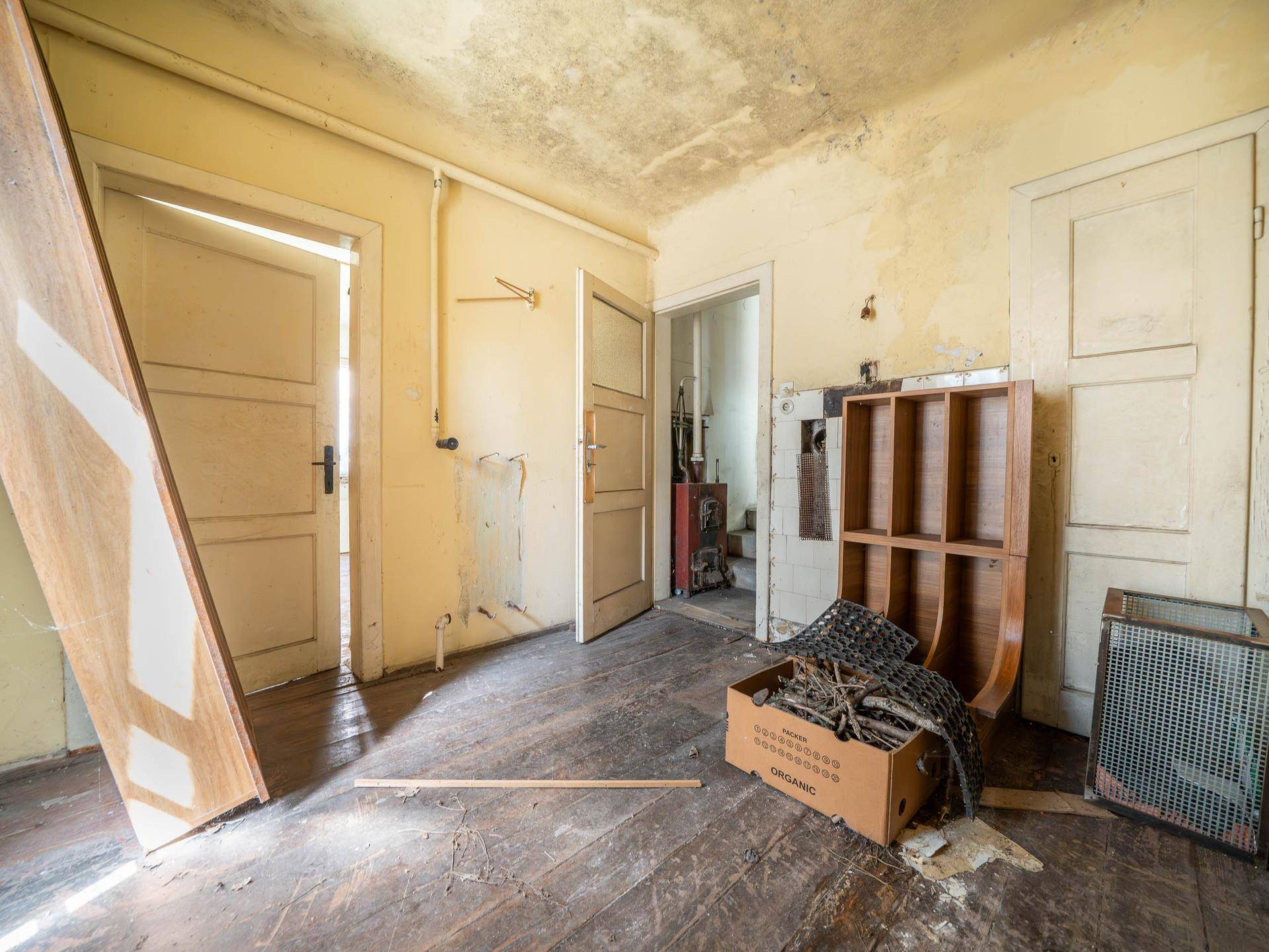 Renovierungsbedürftiger Raum mit Holzboden und sichtbaren Abnutzungsspuren.