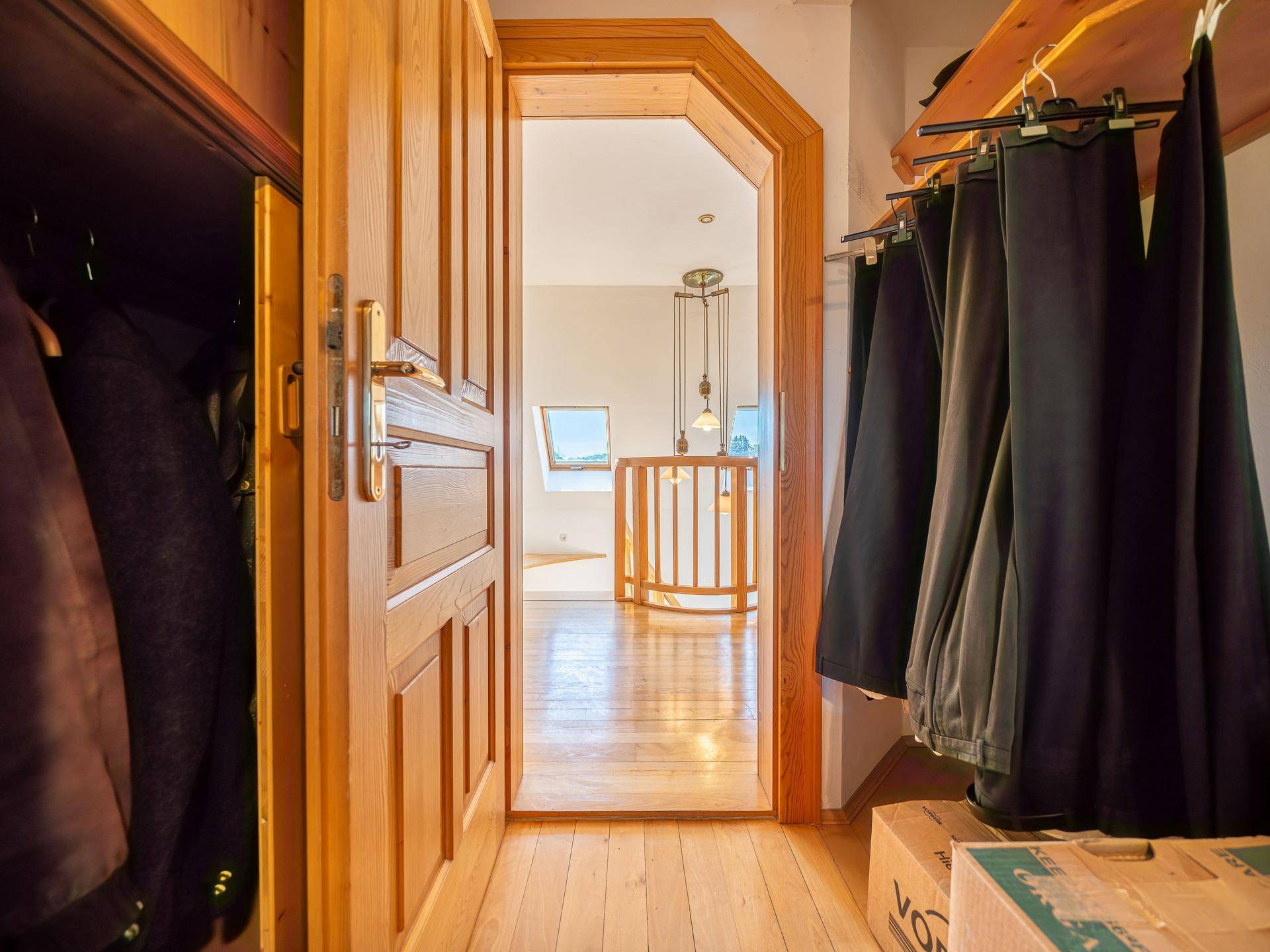Kleiner Flur oder begehbarer Kleiderschrank mit Holzfußboden und Blick in den nächsten Raum.