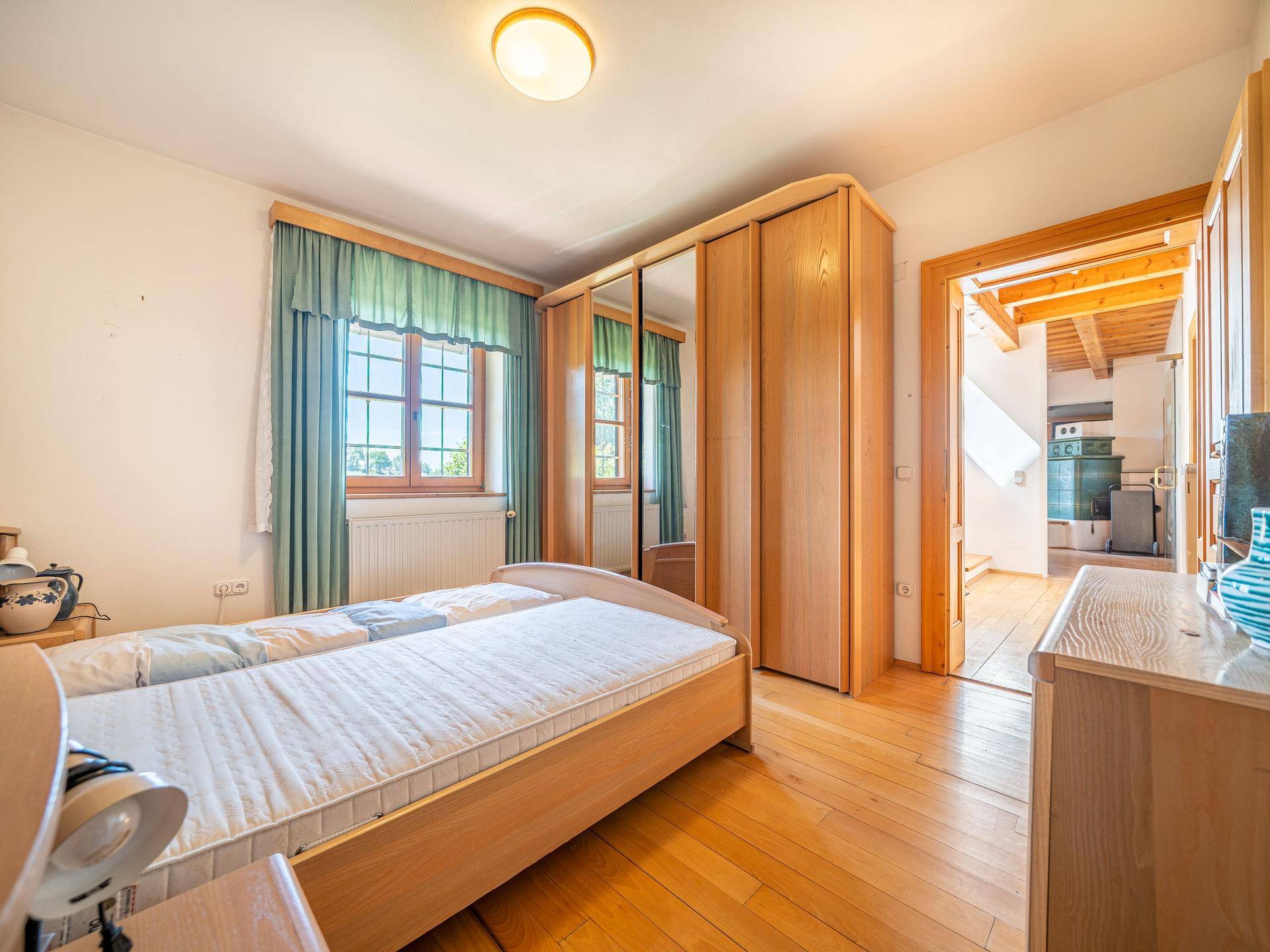 Helles Schlafzimmer mit Holzfußboden, Doppelbett und Kleiderschrank mit Spiegeltüren.