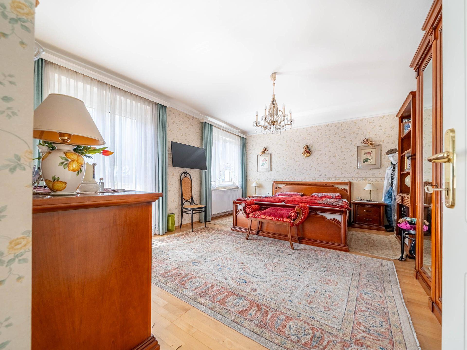 Geräumiges Schlafzimmer mit Doppelbett, Holzboden und klassischer Einrichtung.