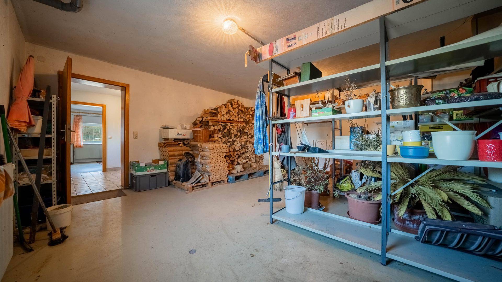 Kellerraum mit Regalen, Holzstapeln und verschiedenen Lagergegenständen.