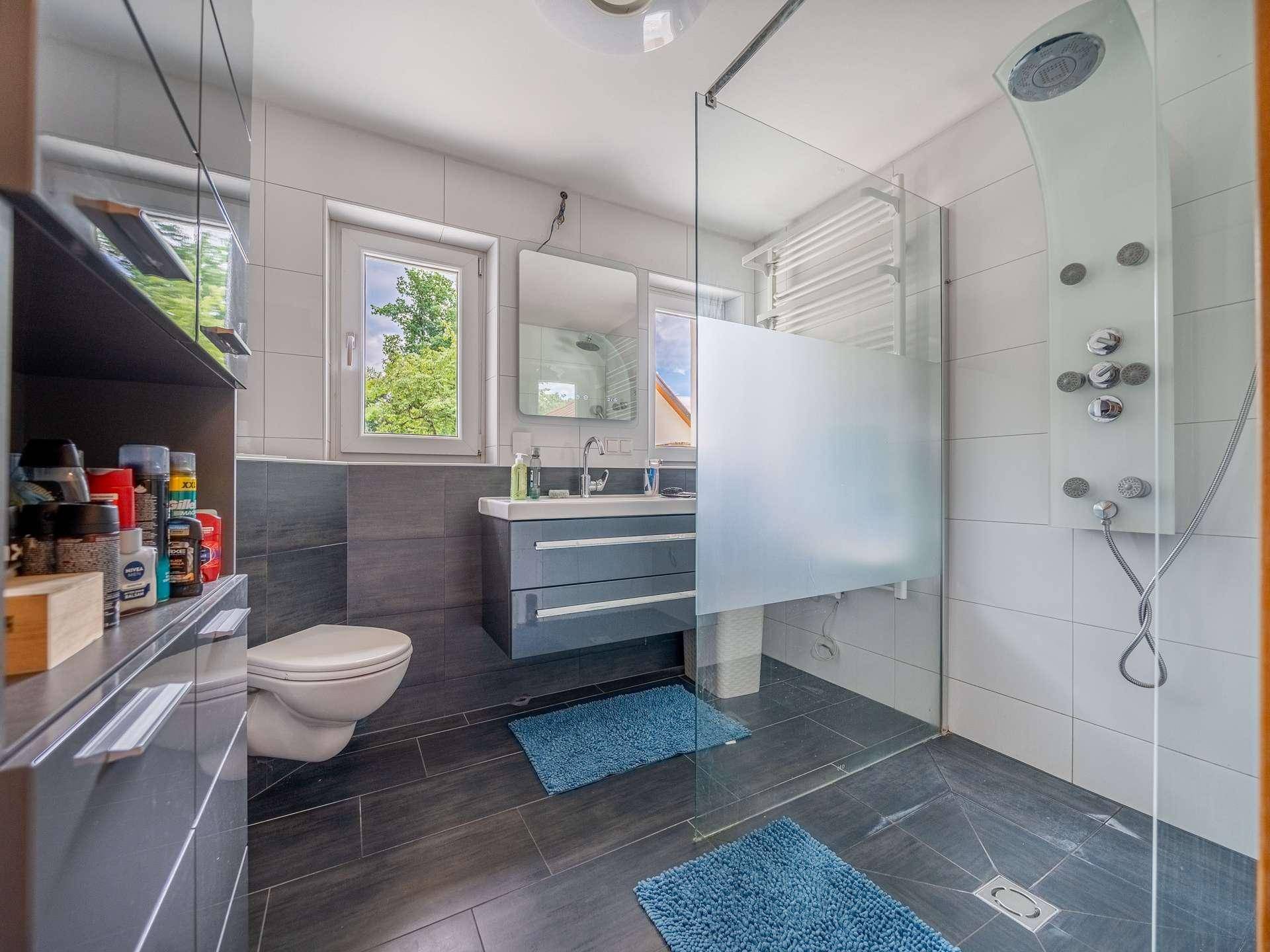 Modernes Badezimmer mit ebenerdiger Dusche, Wand-WC und Fenster.
