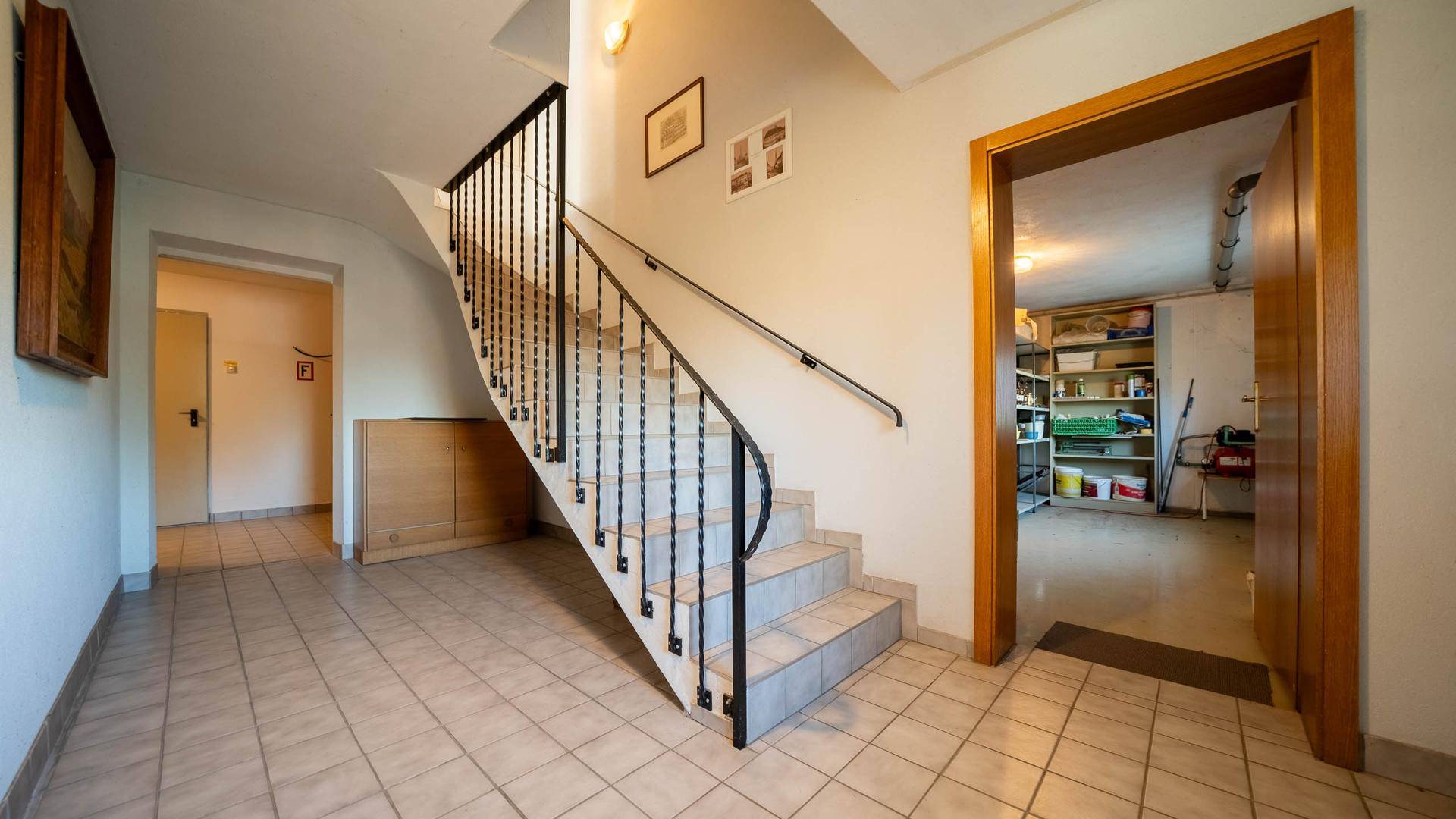 Flur mit Treppe zum Keller, Fliesenboden und Zugang zu weiteren Räumen.