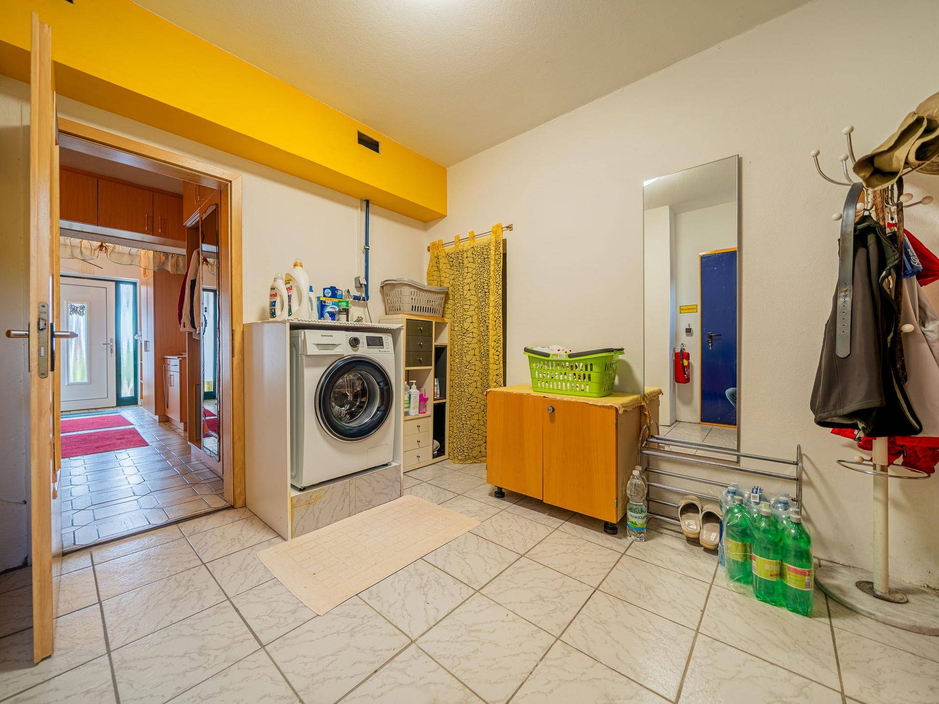 Hauswirtschaftsraum mit Waschmaschine, Spiegel und Garderobe, ideal für den täglichen Gebrauch.
