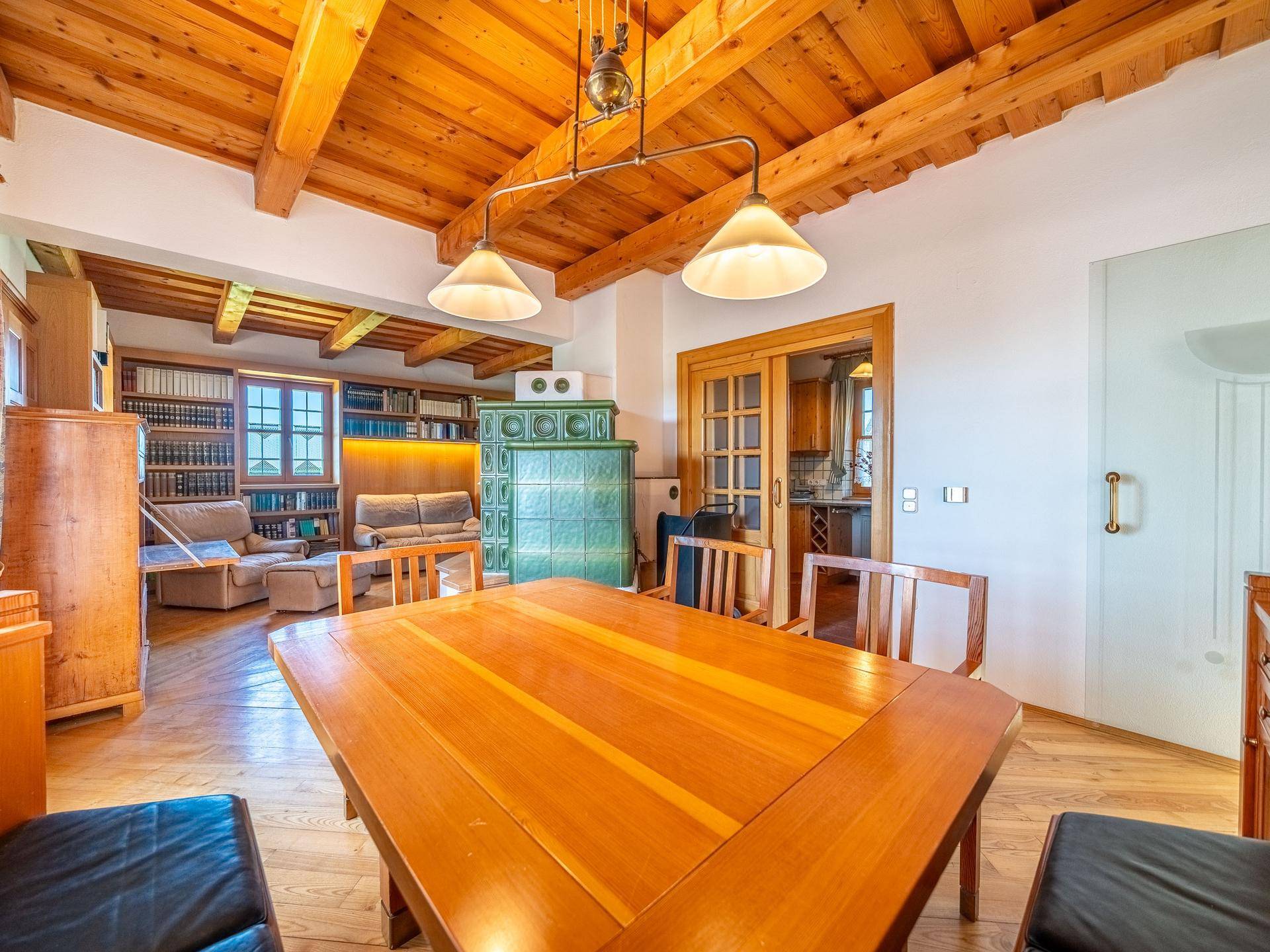 Geräumiger Wohn- und Essbereich mit Holzbalkendecke, großem Esstisch und Bücherregalen.