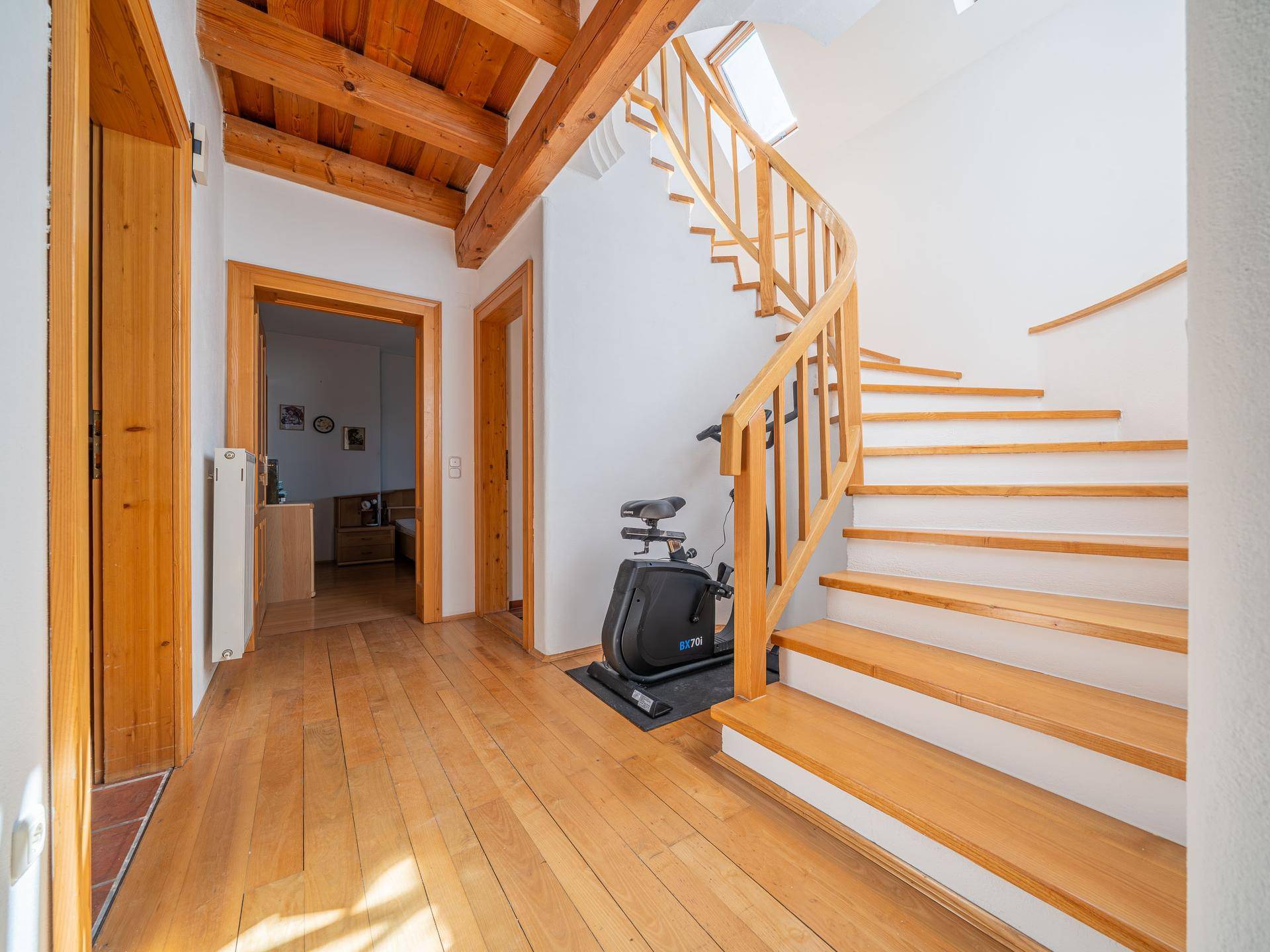 Geräumiger Flur mit Holztreppe, Holzfußboden und Zugang zu verschiedenen Zimmern.